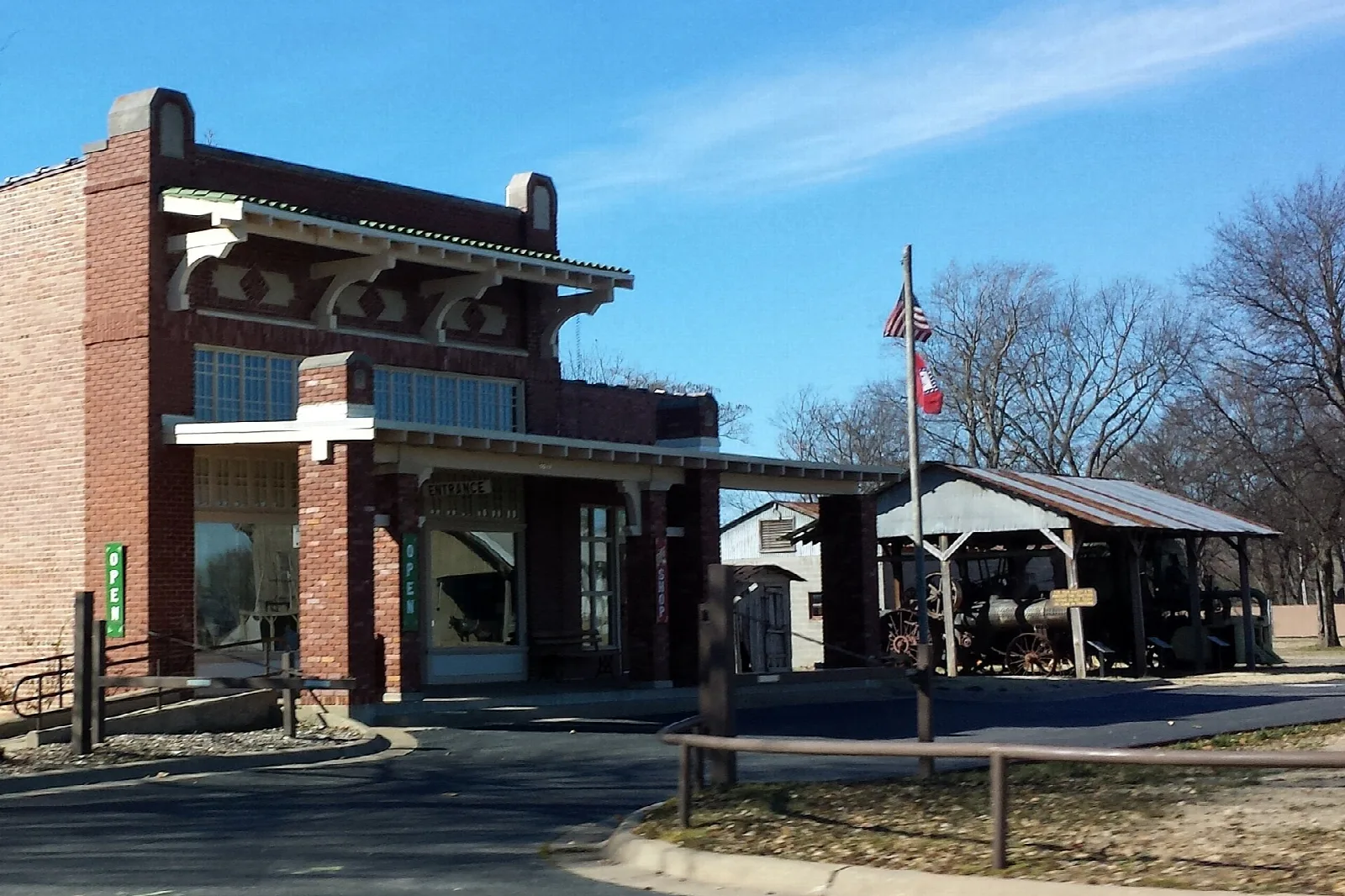 Brick museum building with a covered porch and flag under a blue sky
