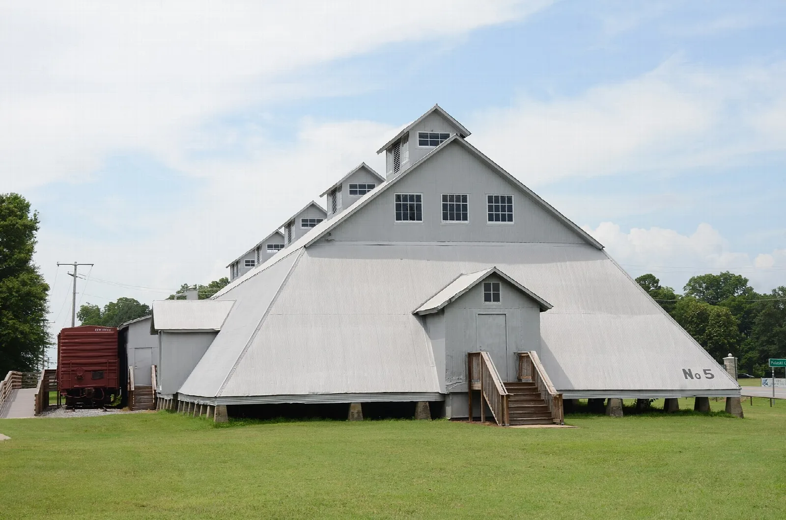 Large pale gray seed warehouse with a gabled roof on a lawn