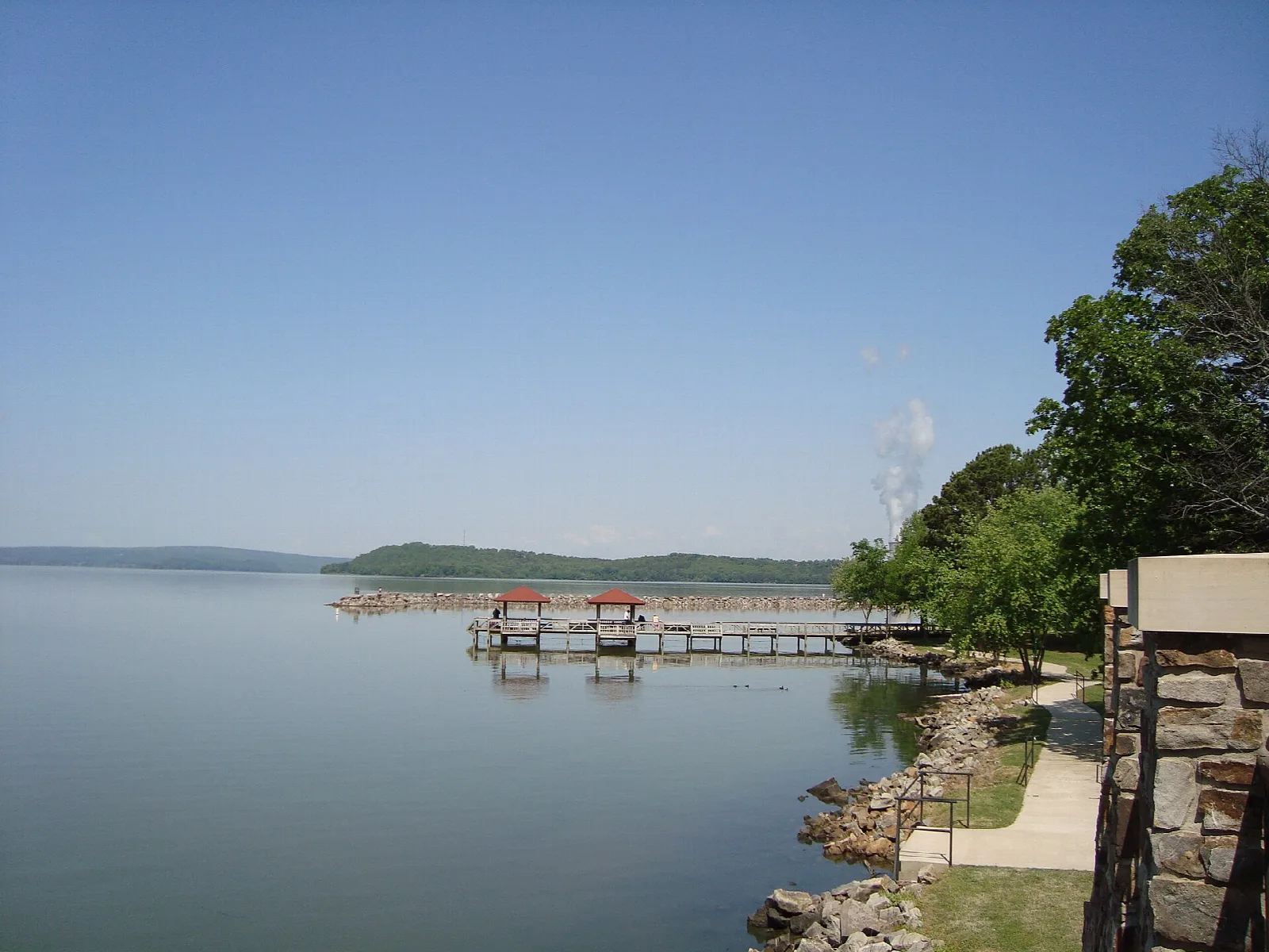 Lake view with a boat dock and a stone wall on the right