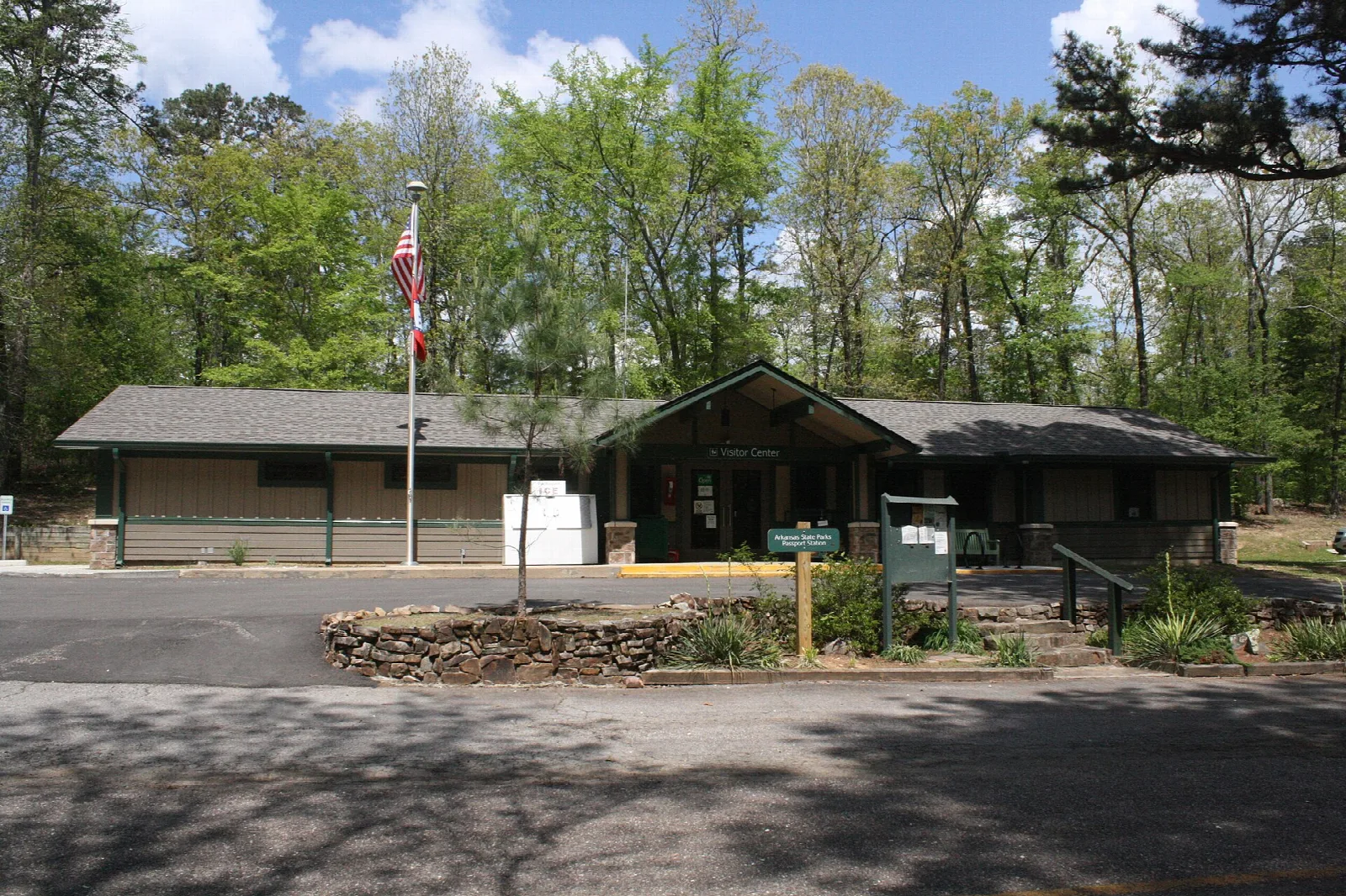 Low visitor center building with a flagpole among trees