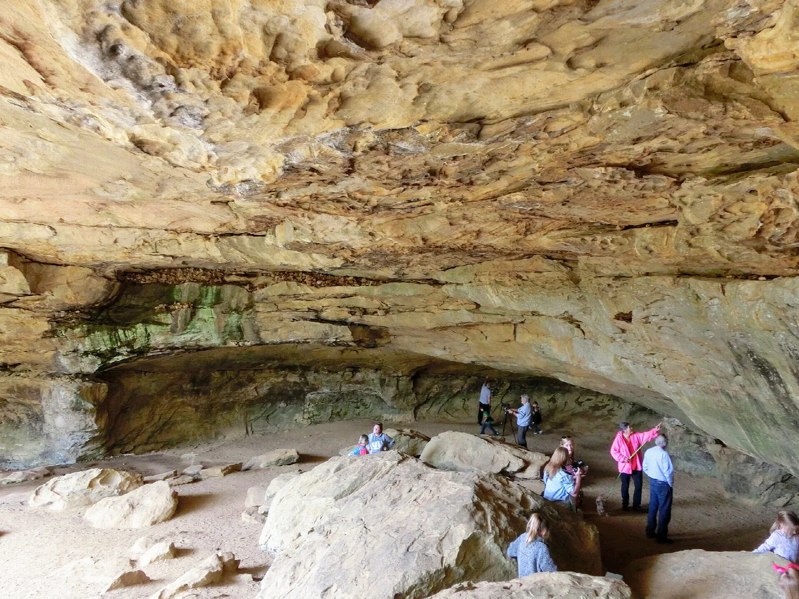 Wide sandstone overhang with visitors standing beneath it