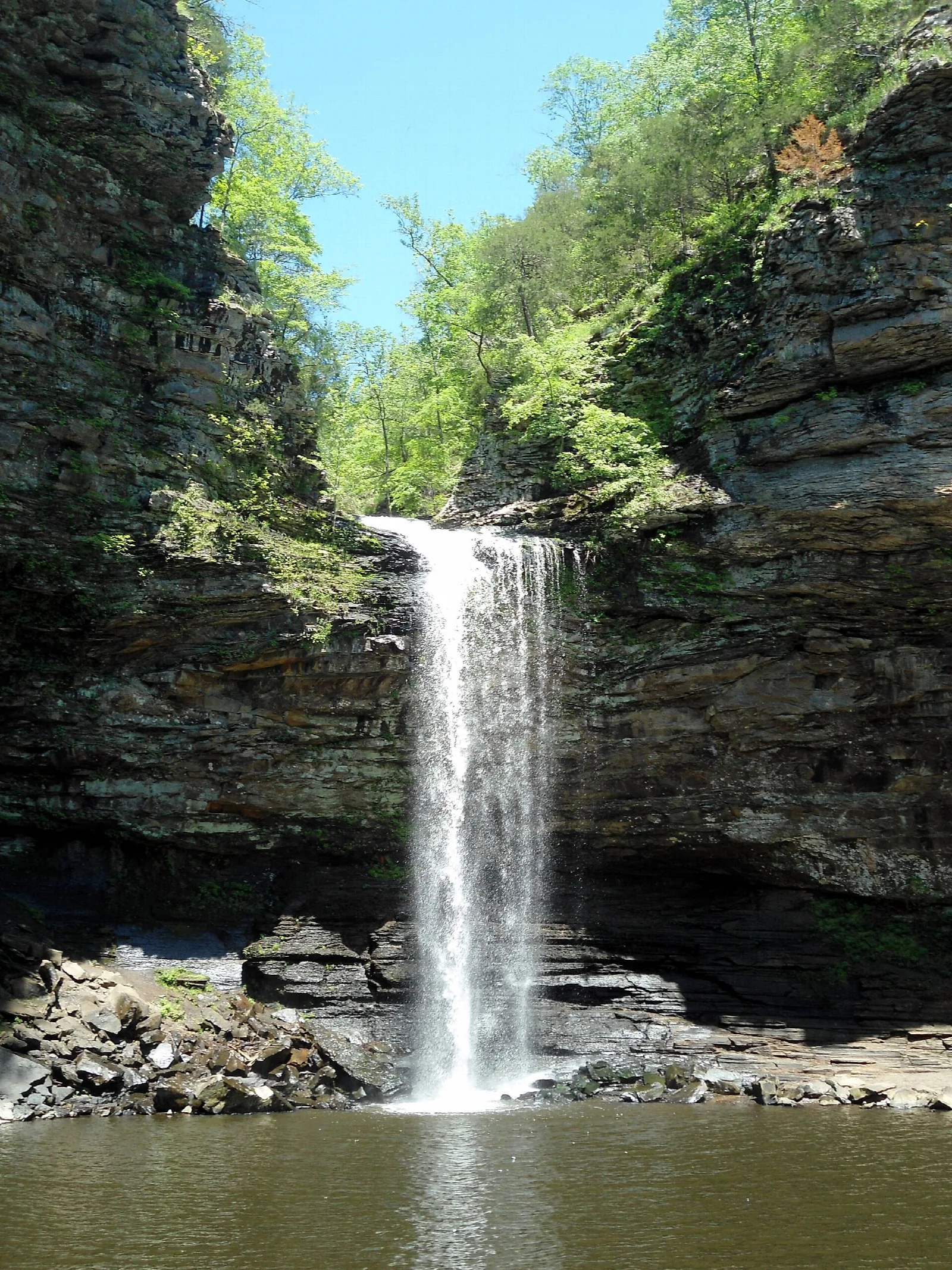 Tall waterfall pouring between dark cliffs into a pool