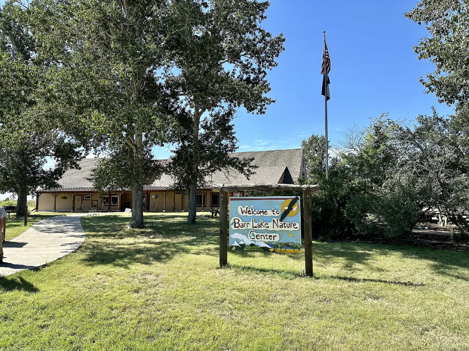 Nature center building behind a lawn, trees and a flagpole