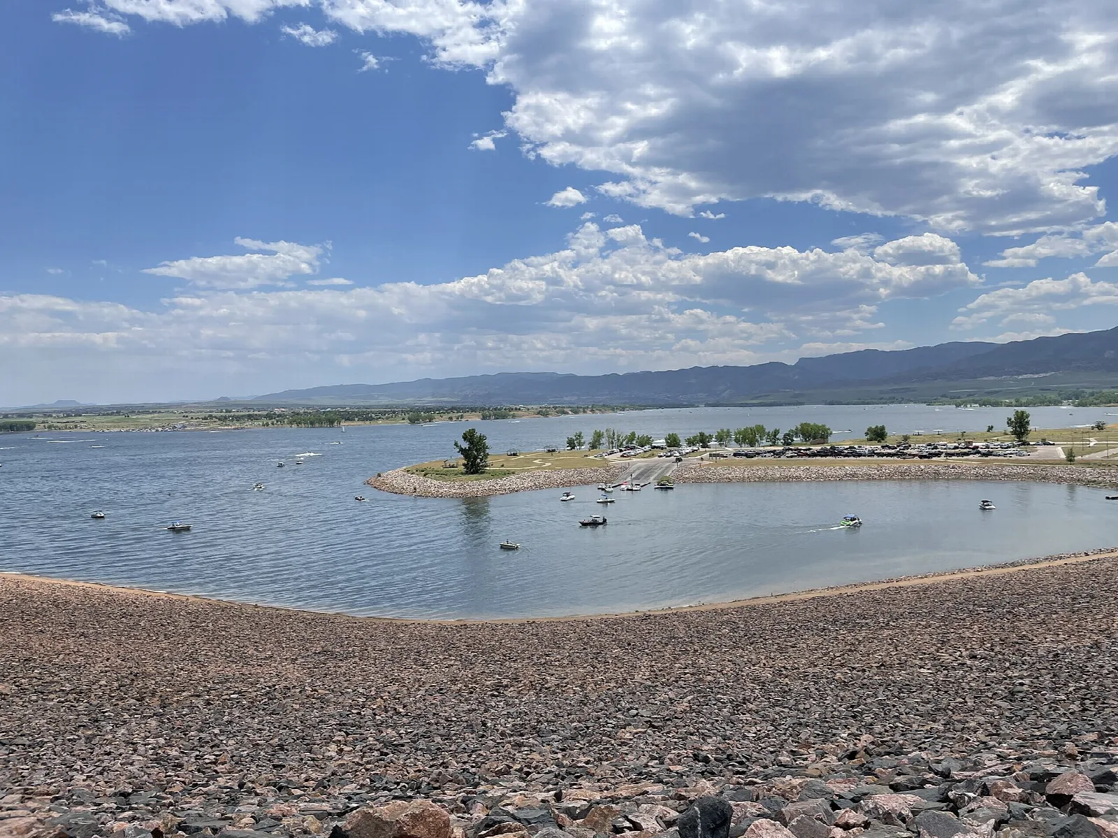 Wide reservoir with a small peninsula and cloudy blue sky