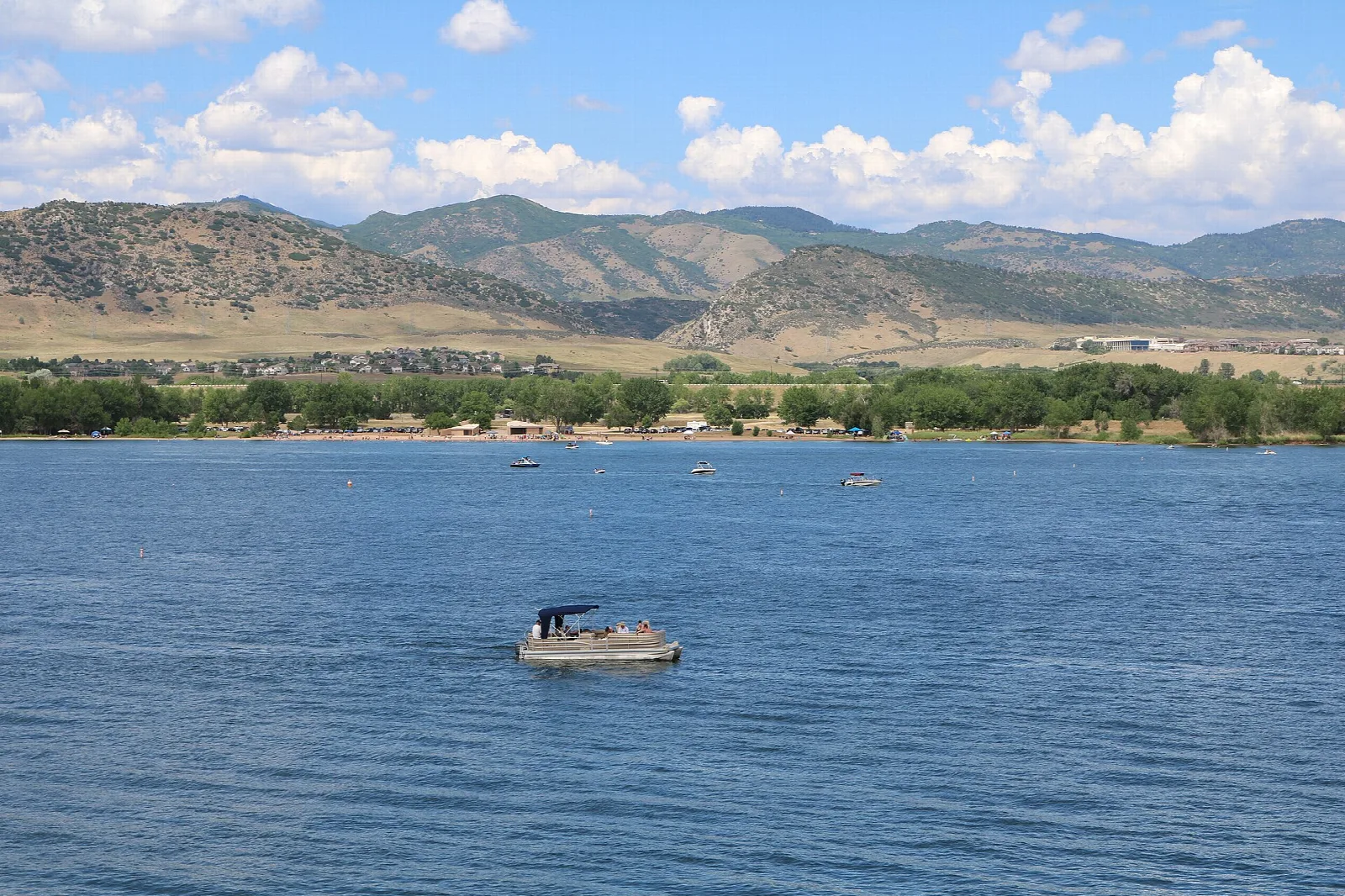 A reservoir with a boat on the water and foothills behind