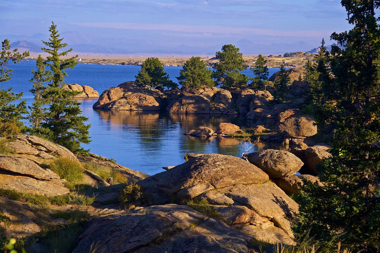 Blue reservoir water among granite rocks and pine trees