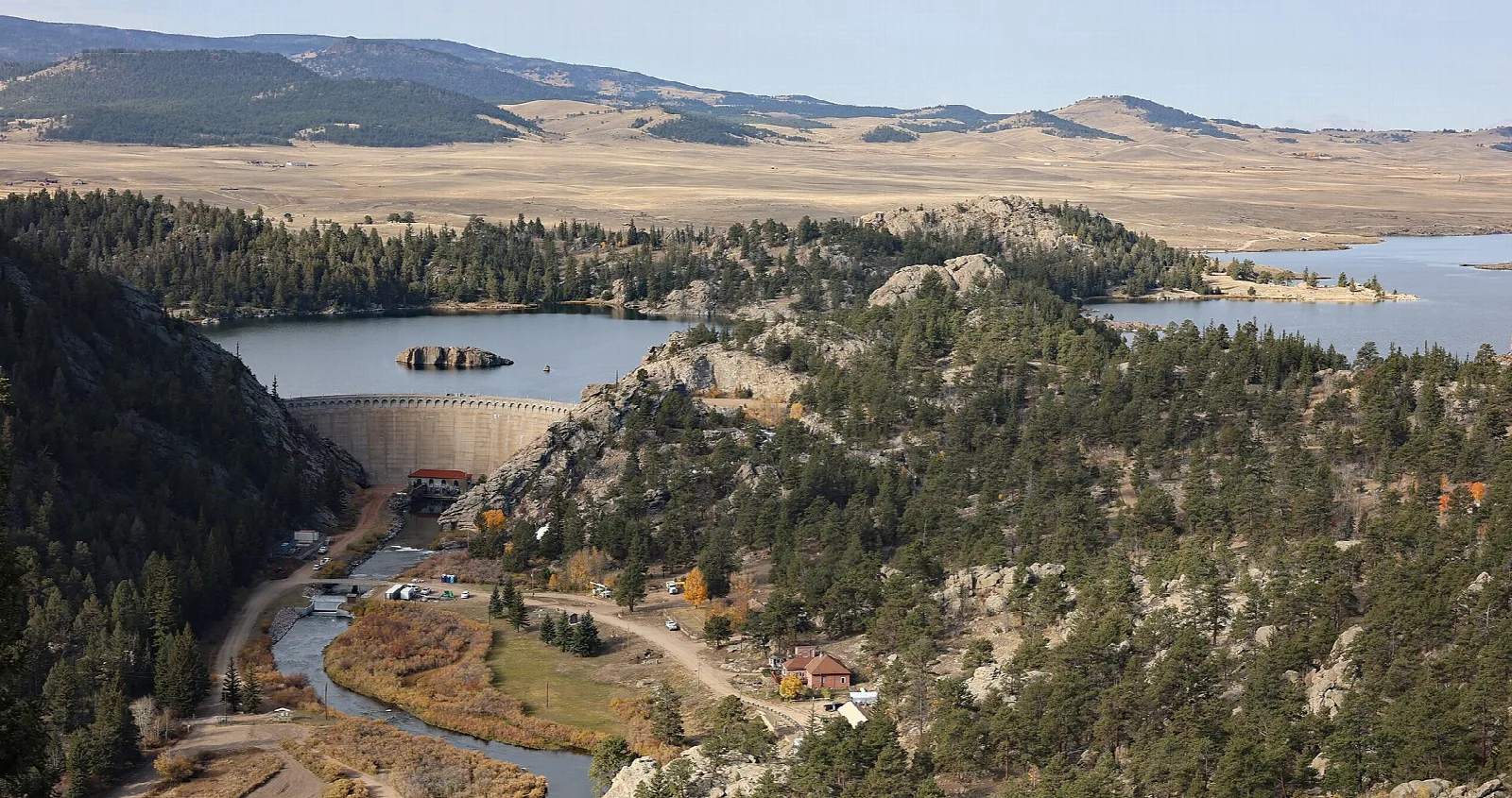 A reservoir and dam in a rocky valley with open high plains beyond