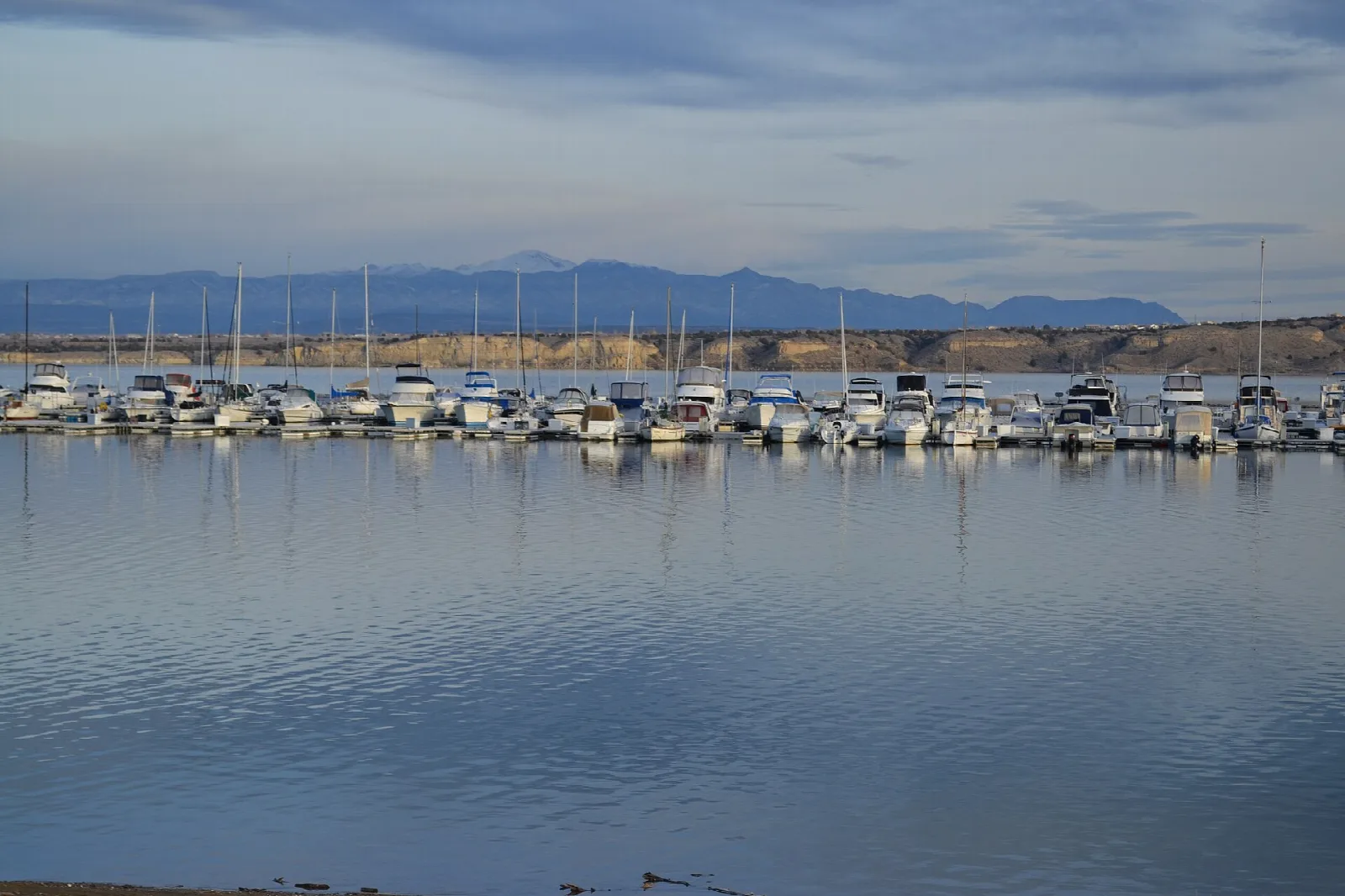 Rows of boats at a marina with mountains behind