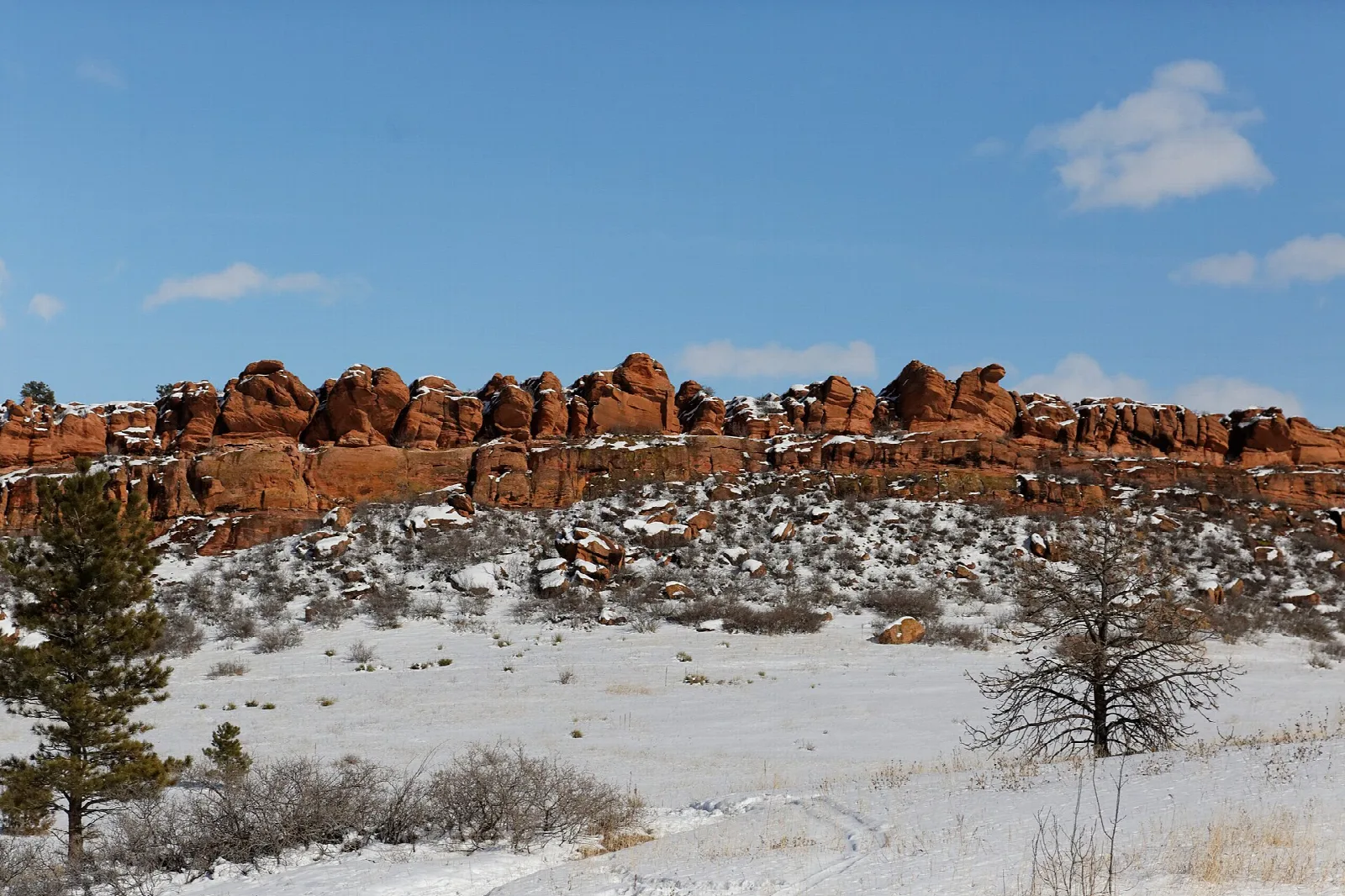 Red sandstone rock outcrops above a snowy hillside