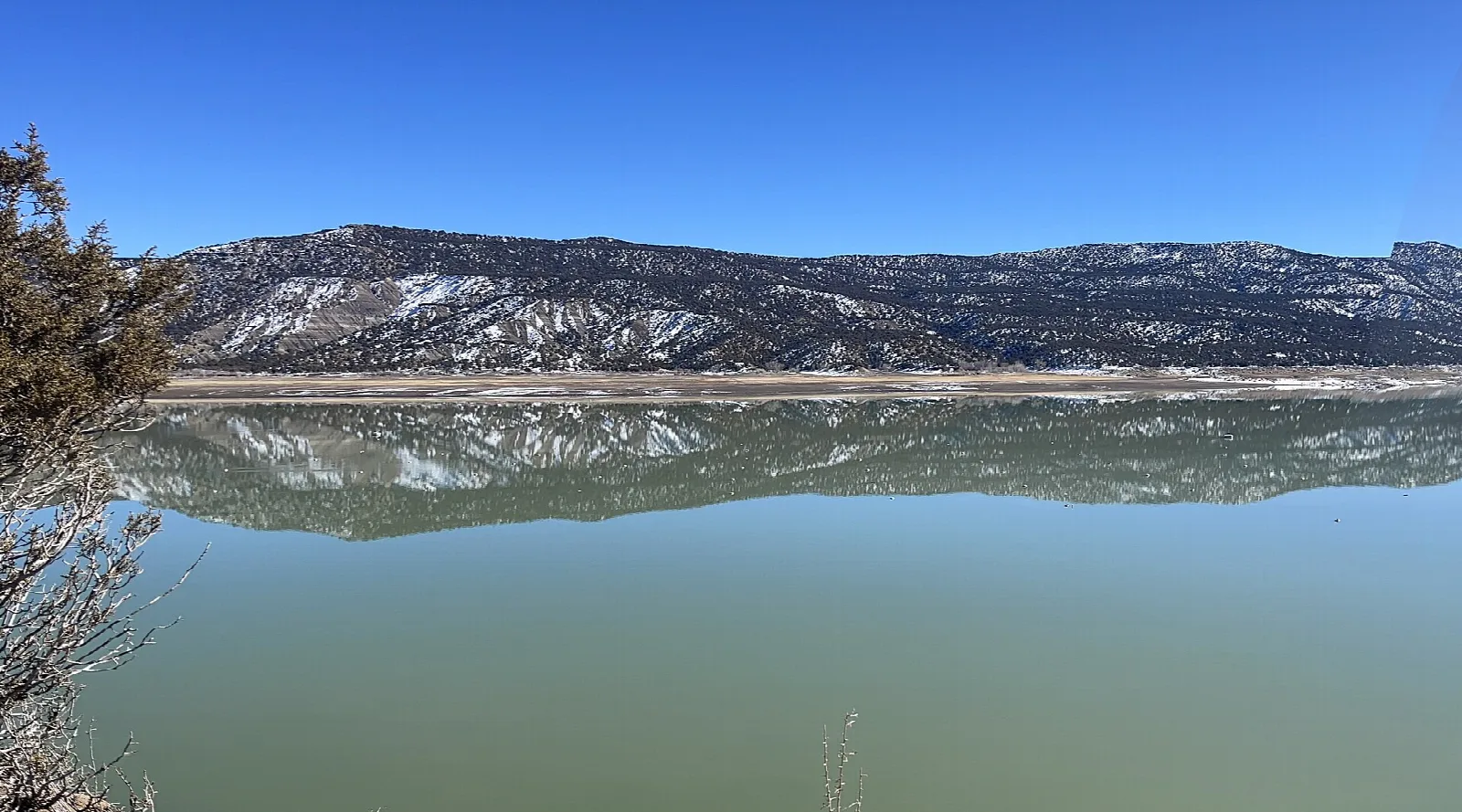 Snowy ridge reflected in still green water