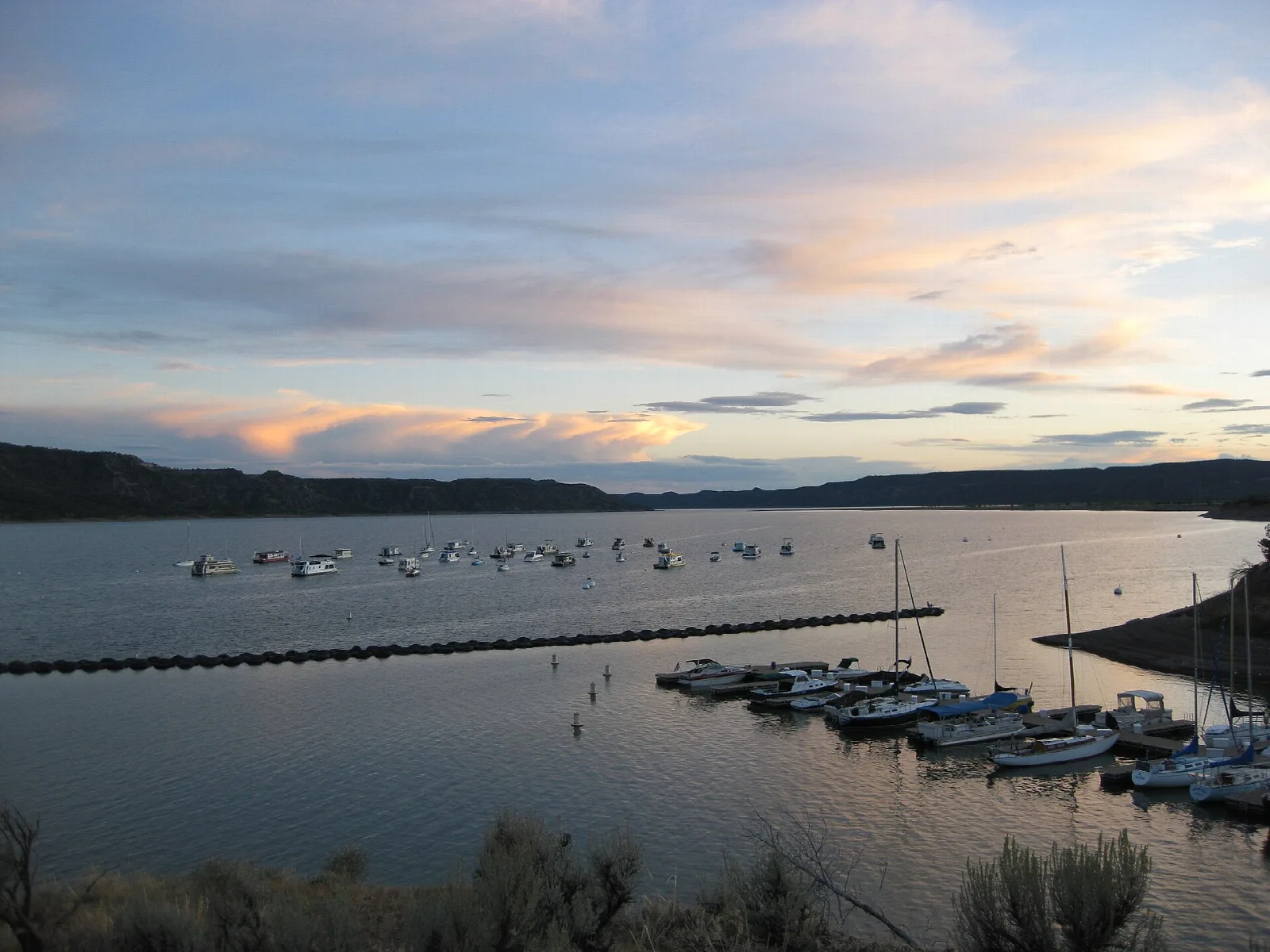Boats moored on a lake at sunset with orange clouds