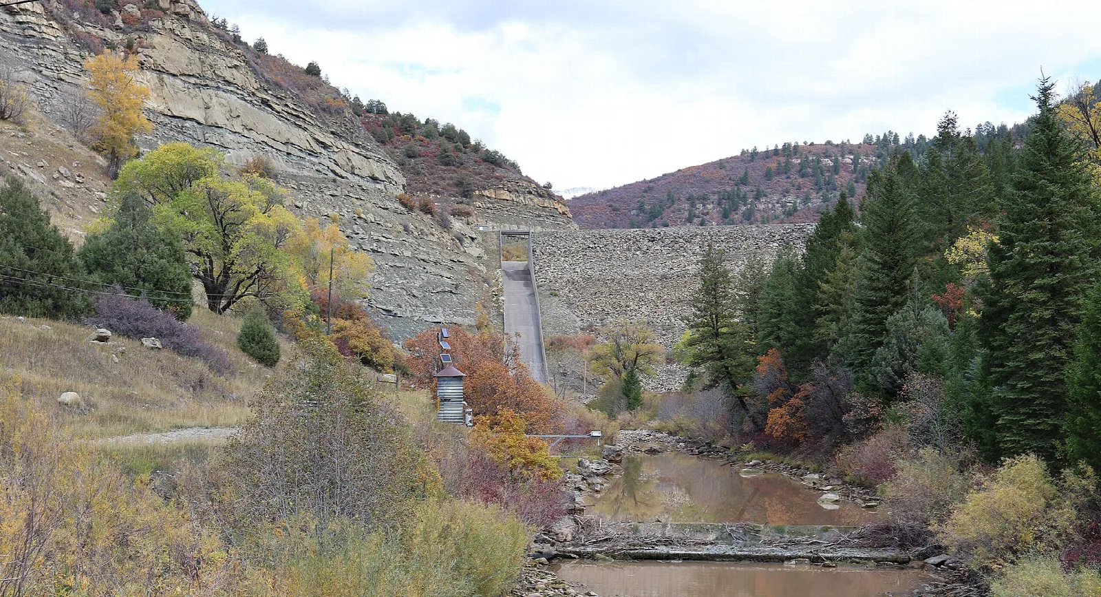 Creek below a rock dam with fall trees and cliffs