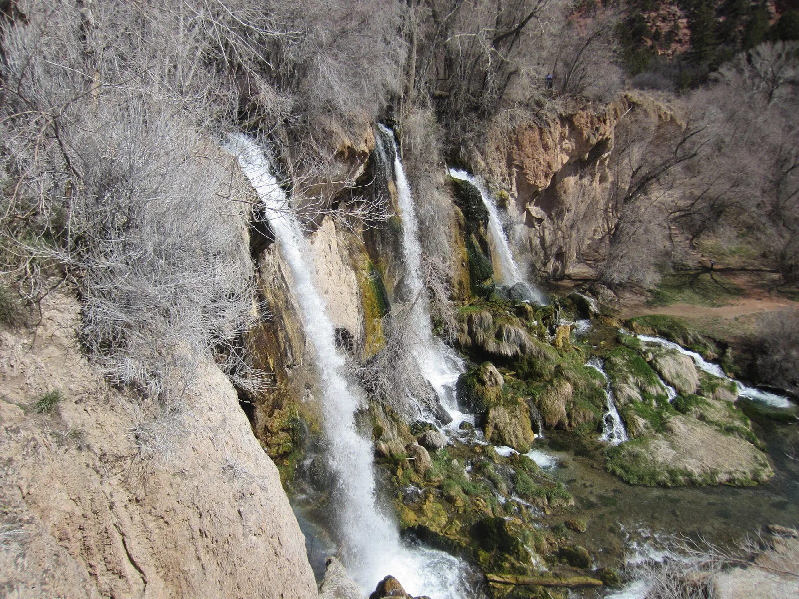 Three waterfalls spilling down a mossy limestone cliff