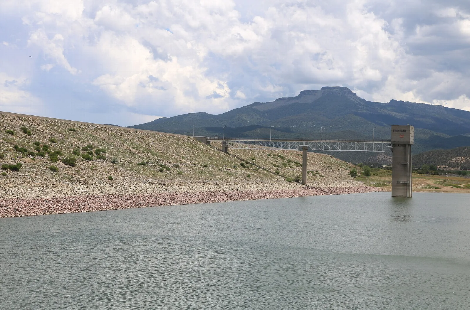 Reservoir with a concrete intake tower and a flat-topped mountain behind