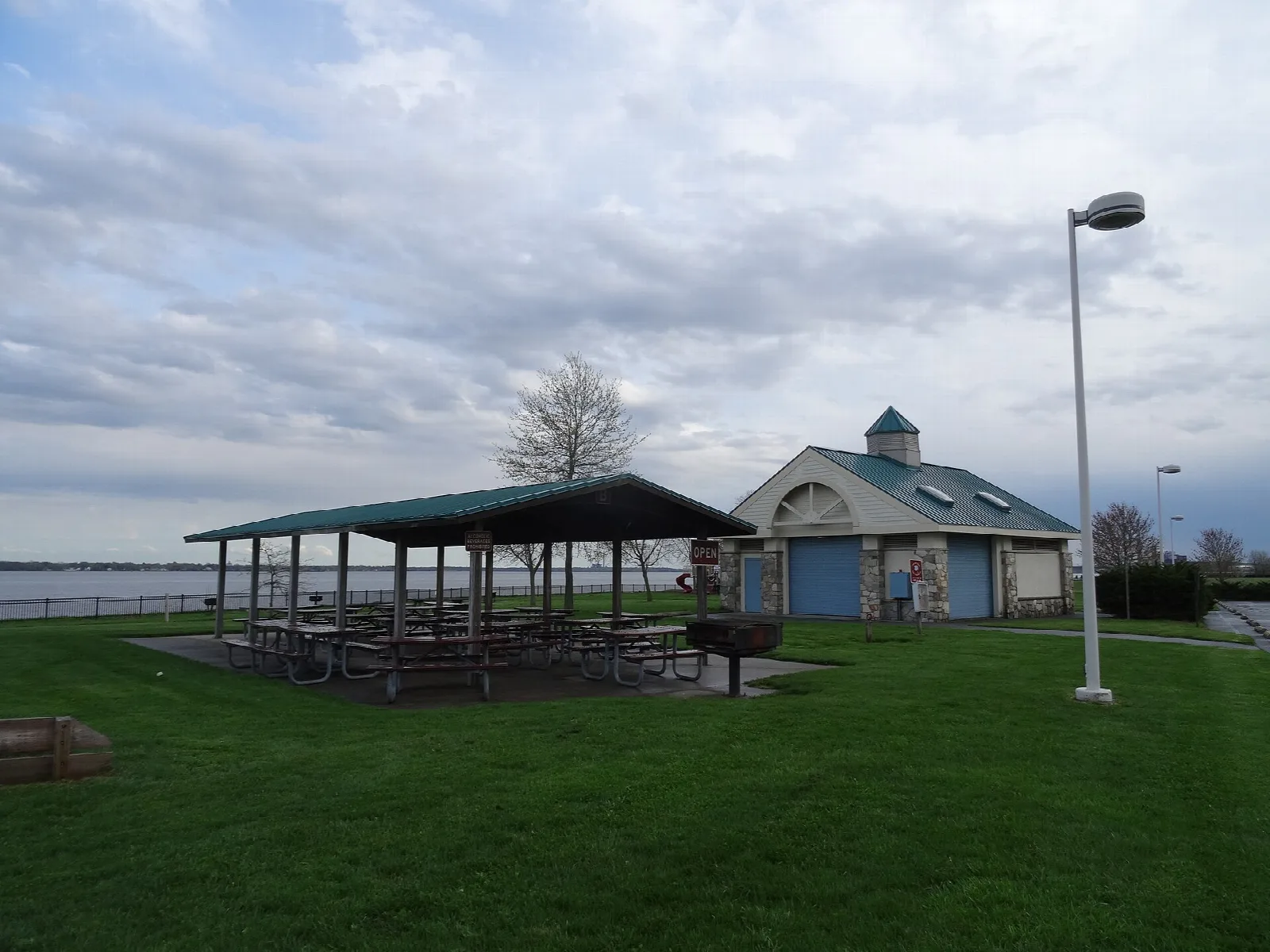 Picnic pavilion and small building on a lawn beside the river