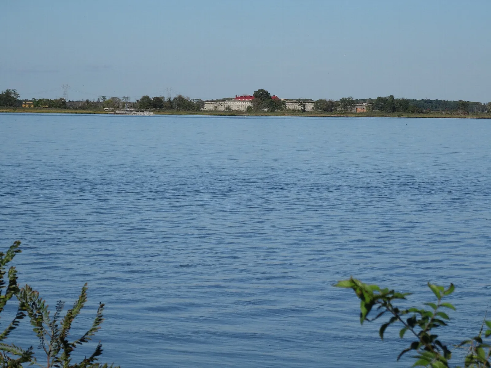 Calm river with a distant shoreline and fort across the water