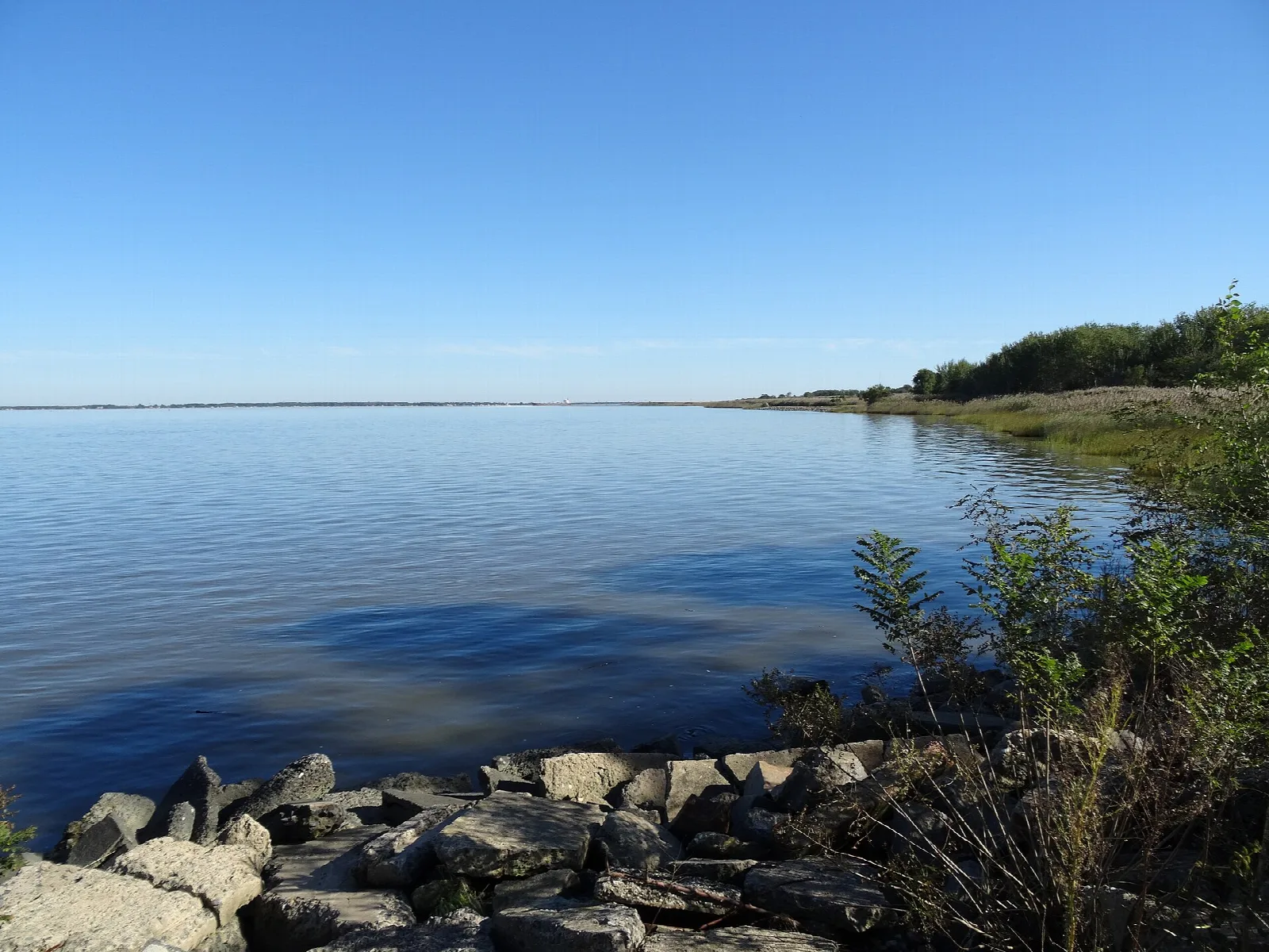 Wide blue river bay with rocks along the shore