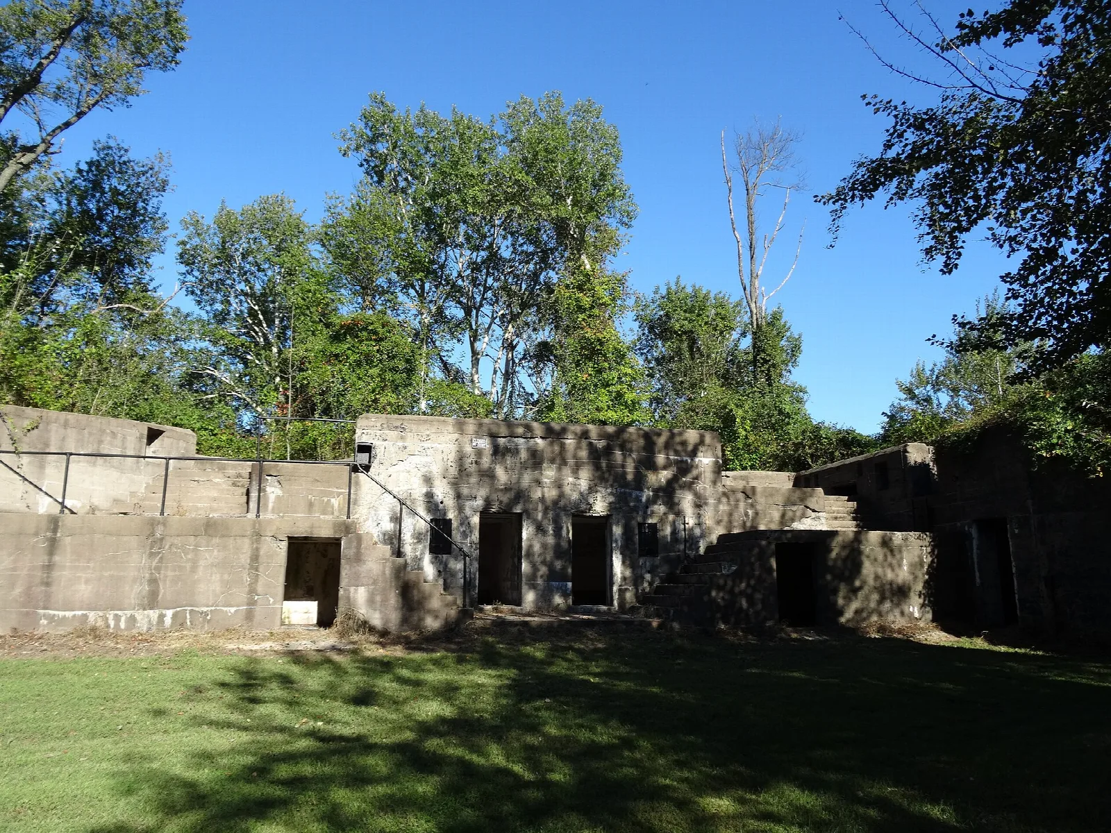 Concrete gun battery ruins beside a green lawn and trees