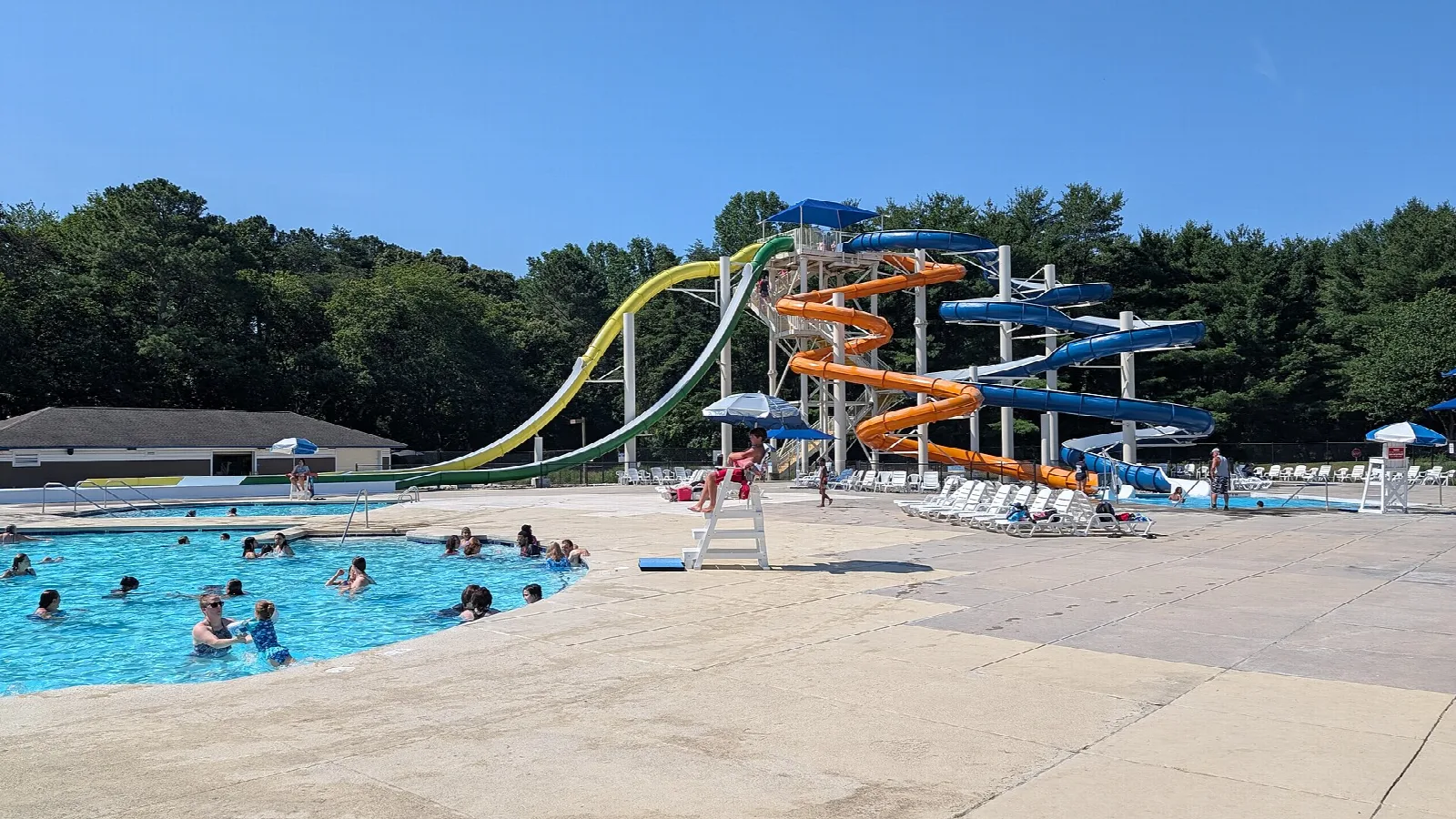 Swimming pool with water slides and swimmers, trees behind