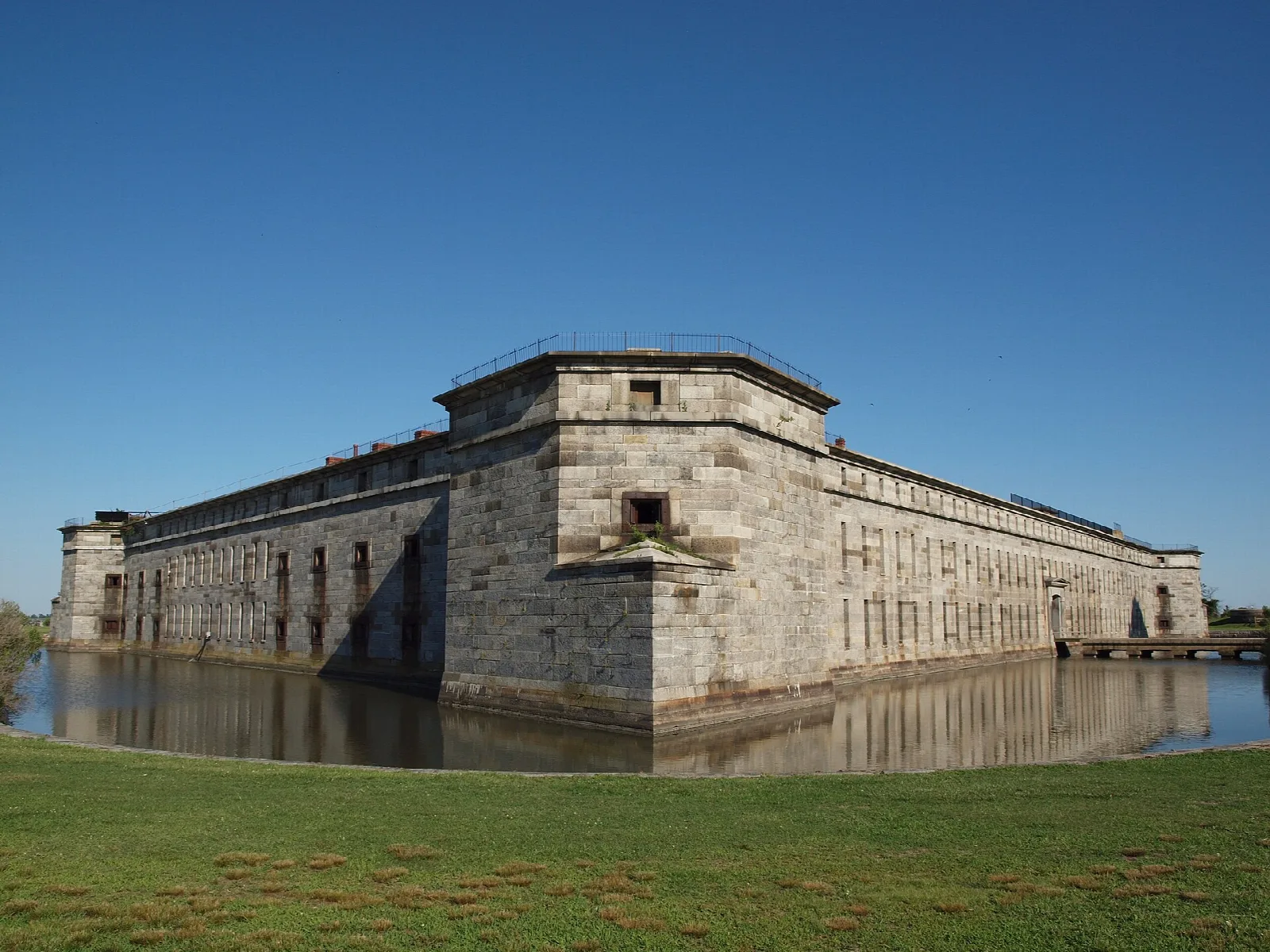 Large stone fort beside a moat with green grass in front