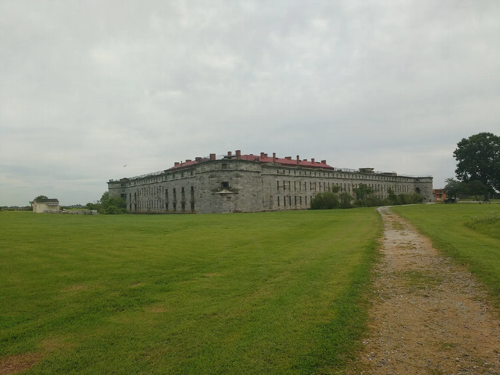 Long stone fort seen across a green lawn and dirt path