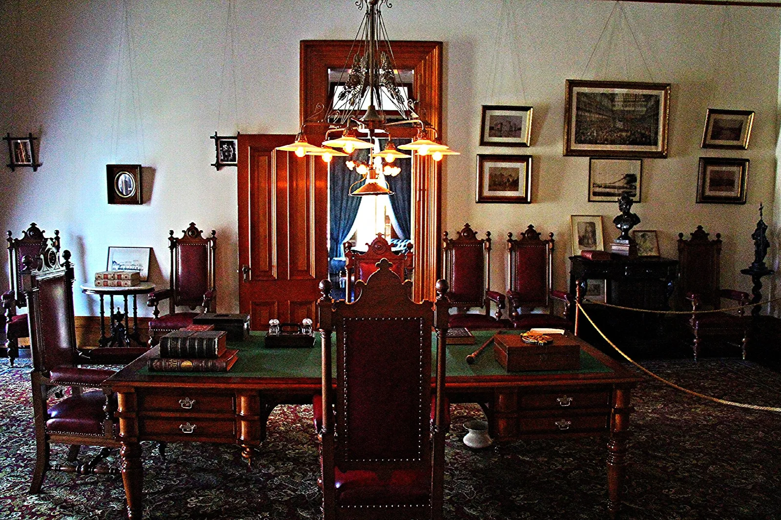 Study with a wooden desk, chairs and framed pictures on the wall