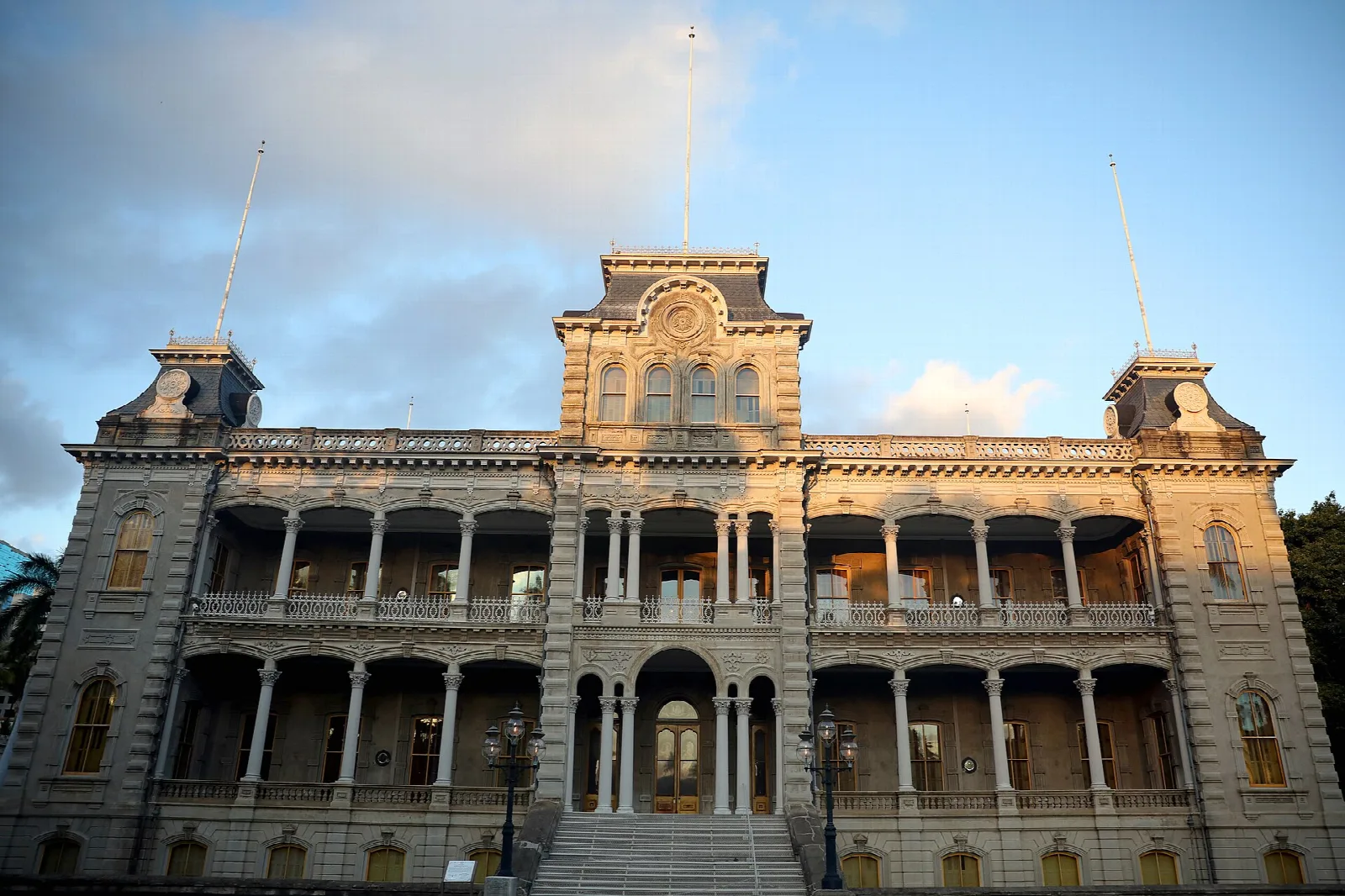 Front of the multi-story palace with balconies, lit by warm evening light