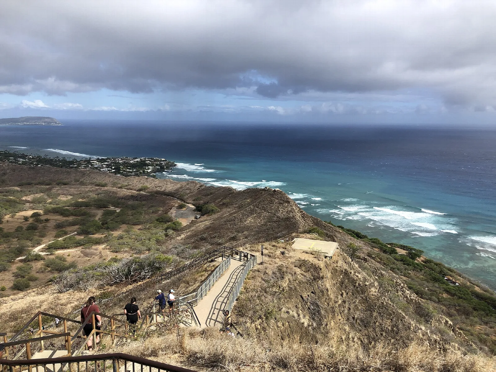 Hikers on a stairway along a dry ridge above the ocean