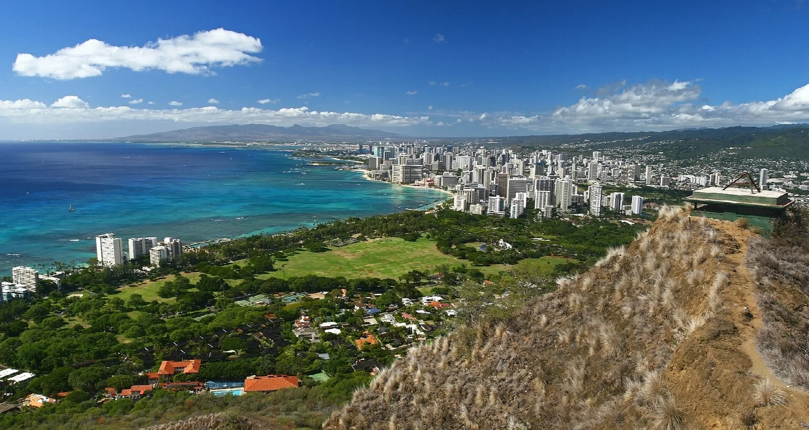 Waikiki shoreline and high-rises seen from the crater rim, with a ridge in the foreground