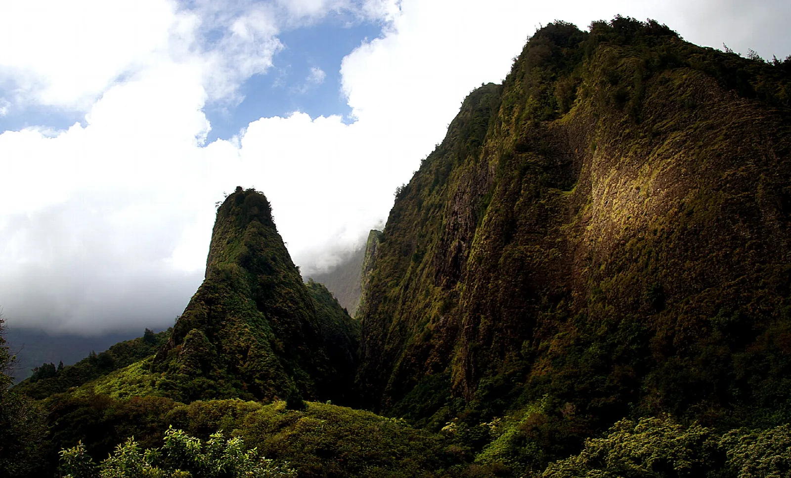 Steep green peaks with sunlit cliff faces above the valley