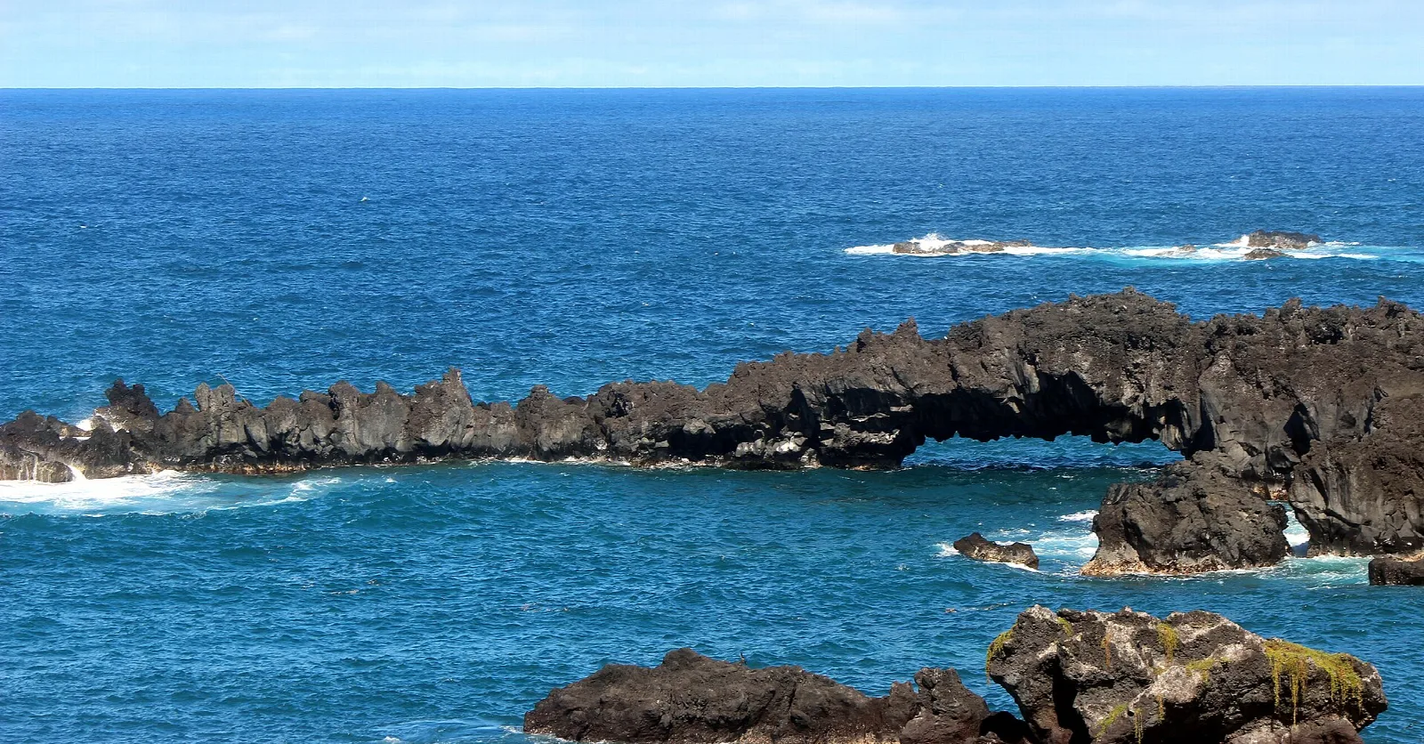 Natural black lava arch over blue ocean