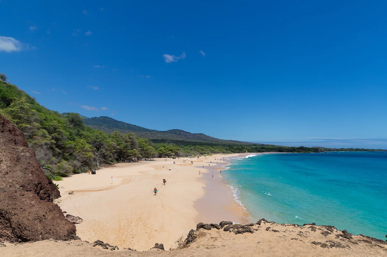 Wide sandy beach and turquoise water seen from a rocky bluff