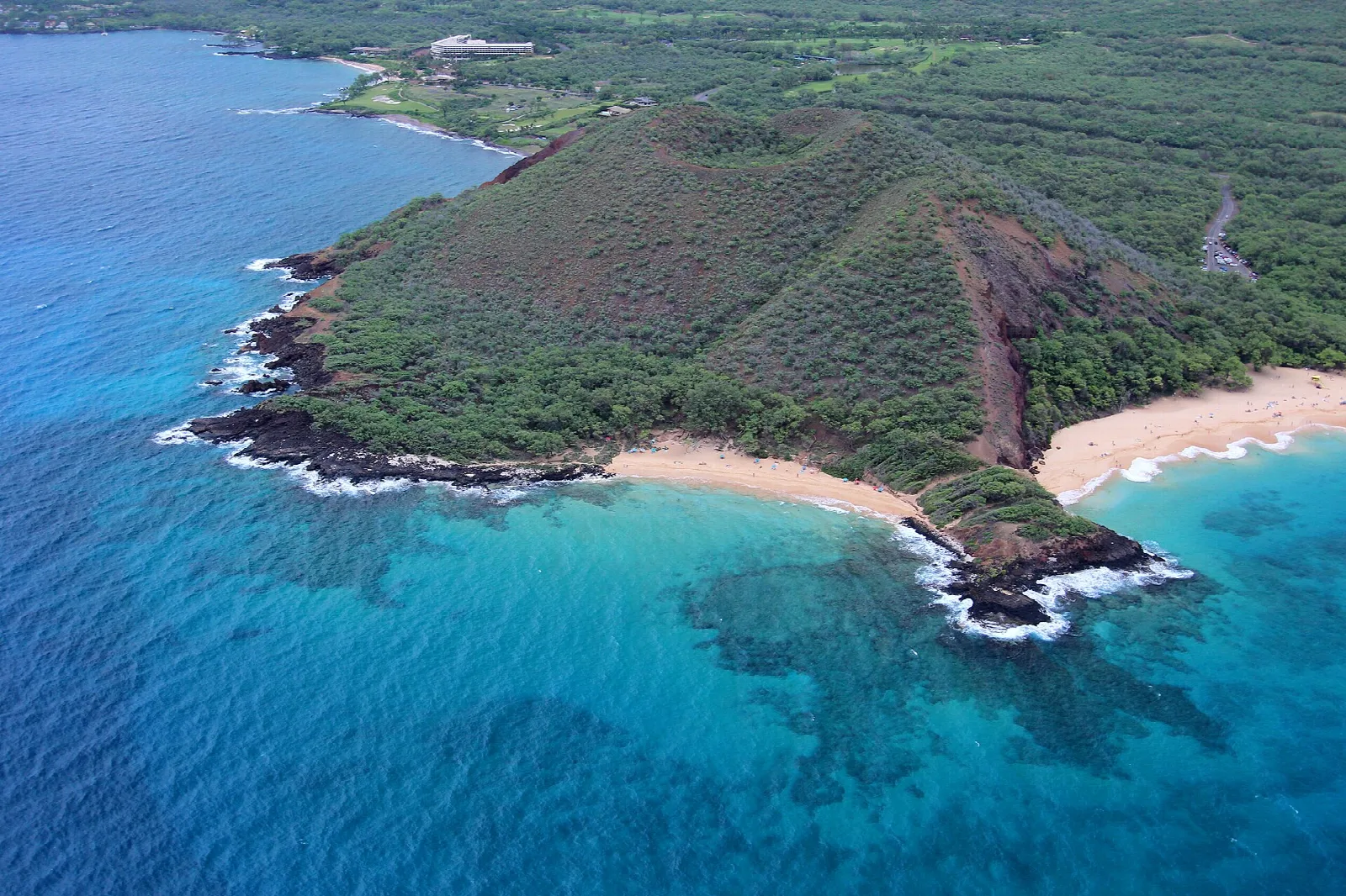 Aerial view of the green cinder cone and a small beach in blue water