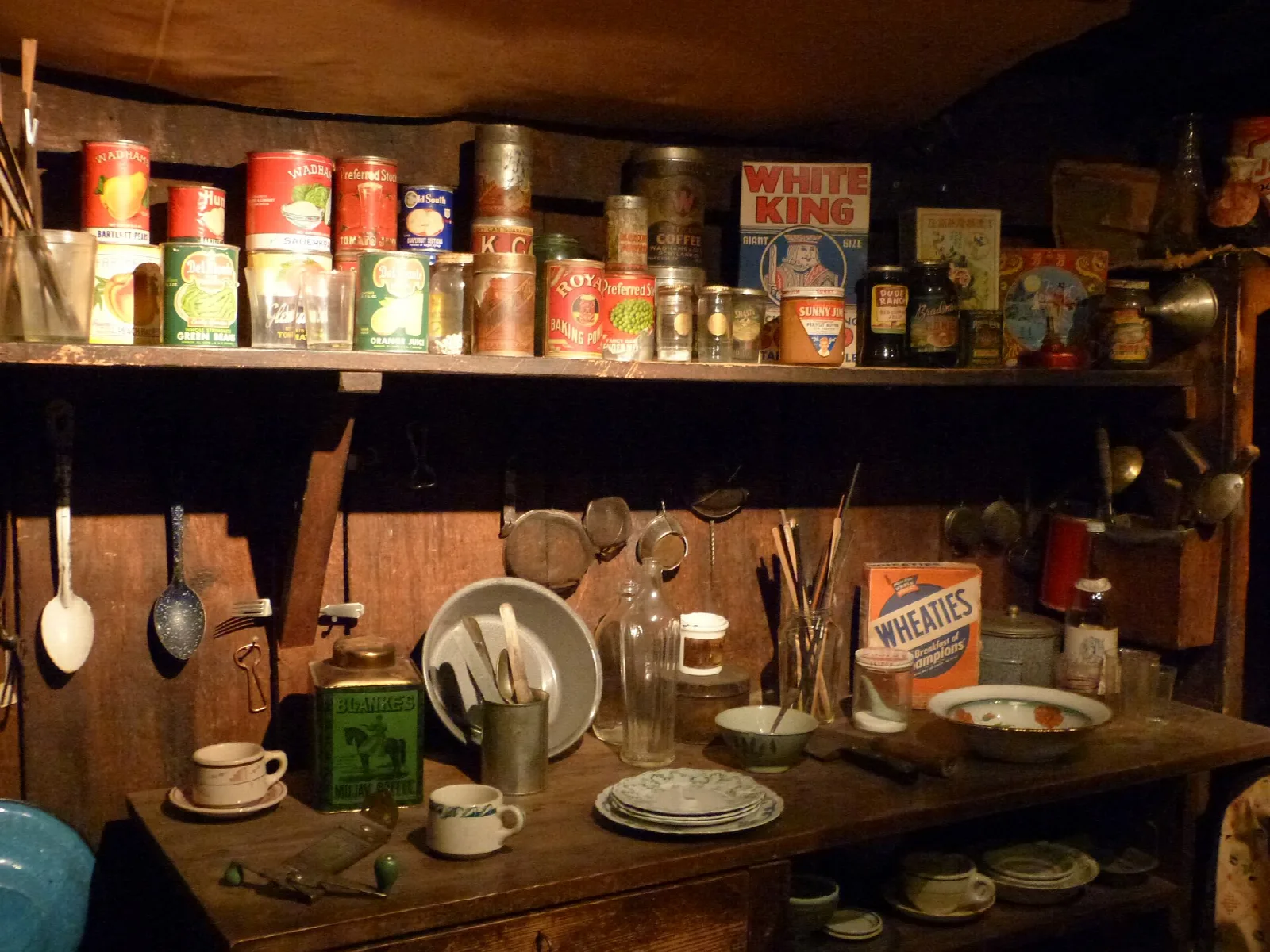Shelf of tins, dishes and cooking tools in the old kitchen