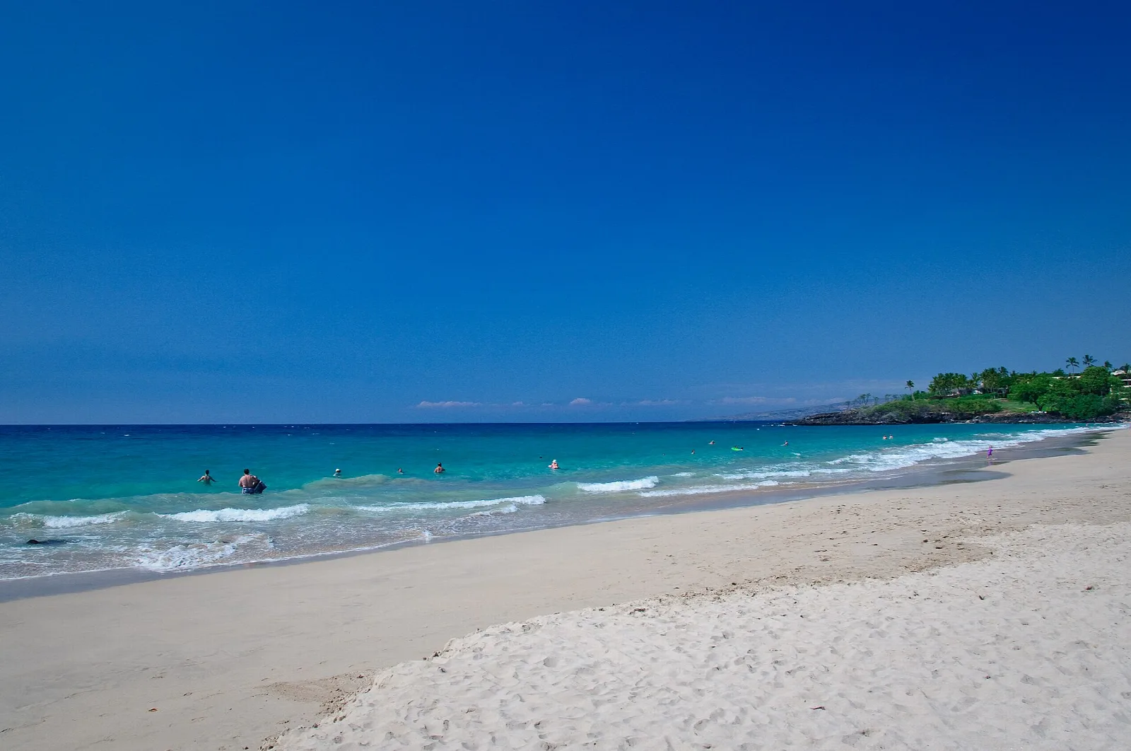 White sand beach and teal water under a deep blue sky