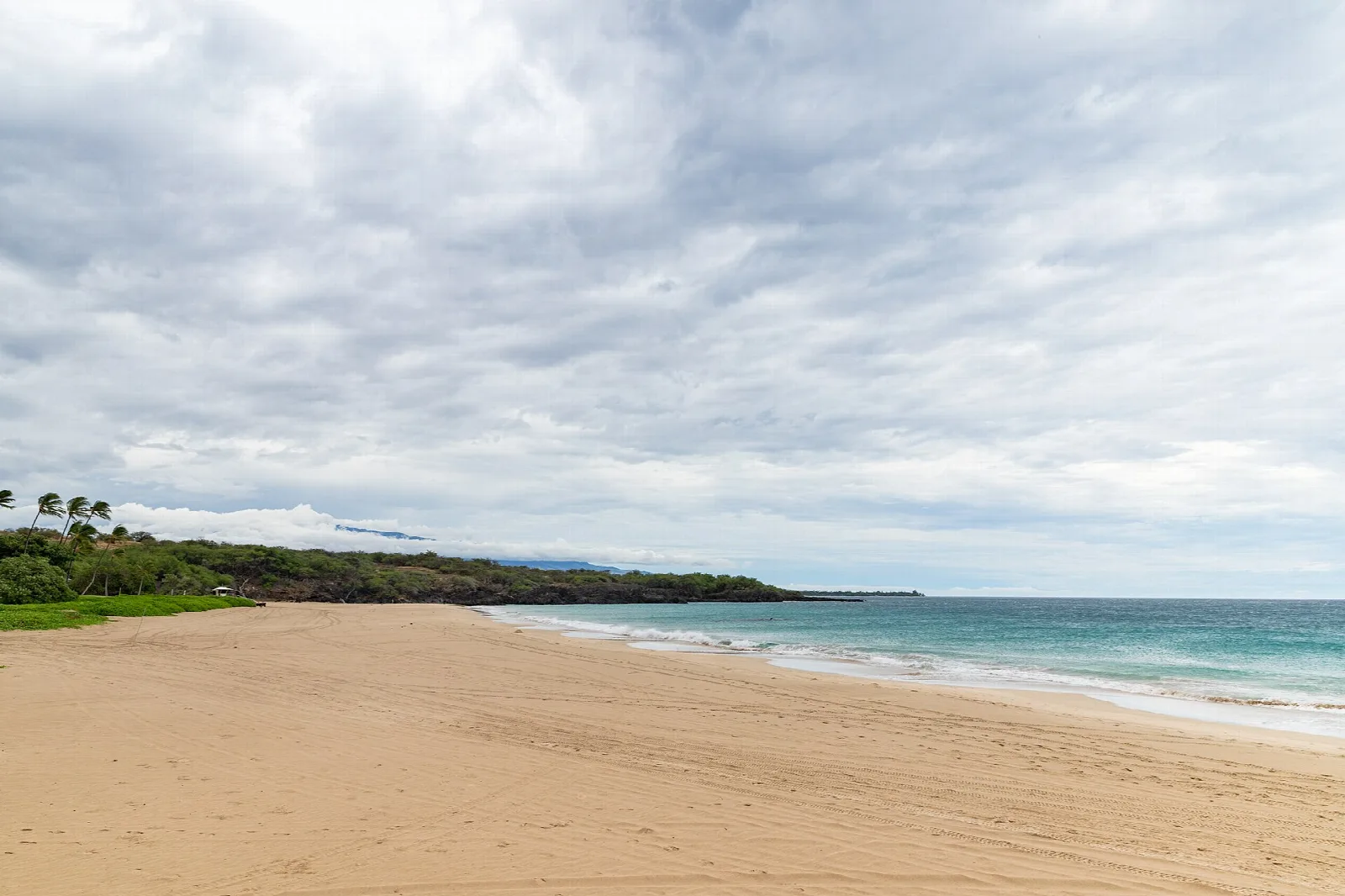 Long empty sandy beach meeting turquoise water