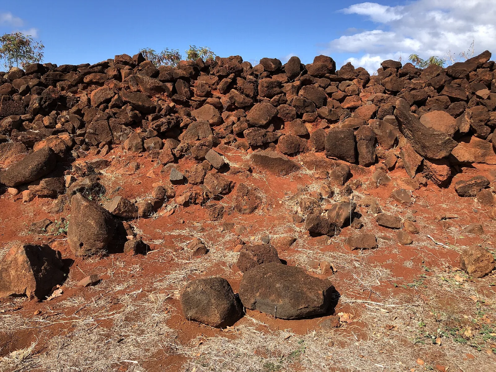 Piled red-brown lava rock under a blue sky