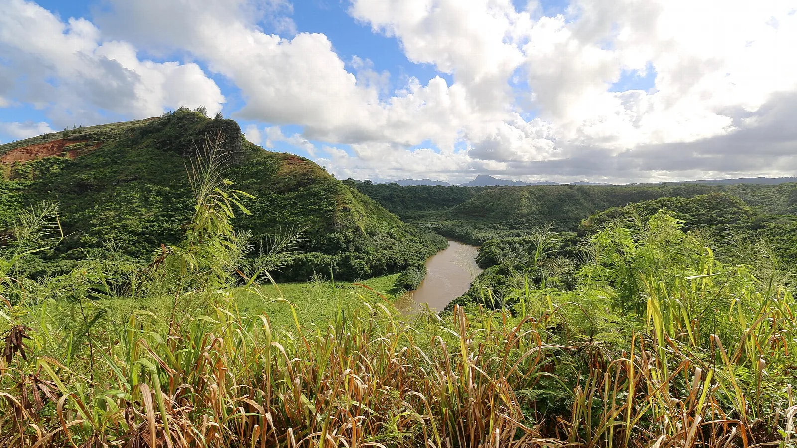 A grassy hill above a river in a wide valley