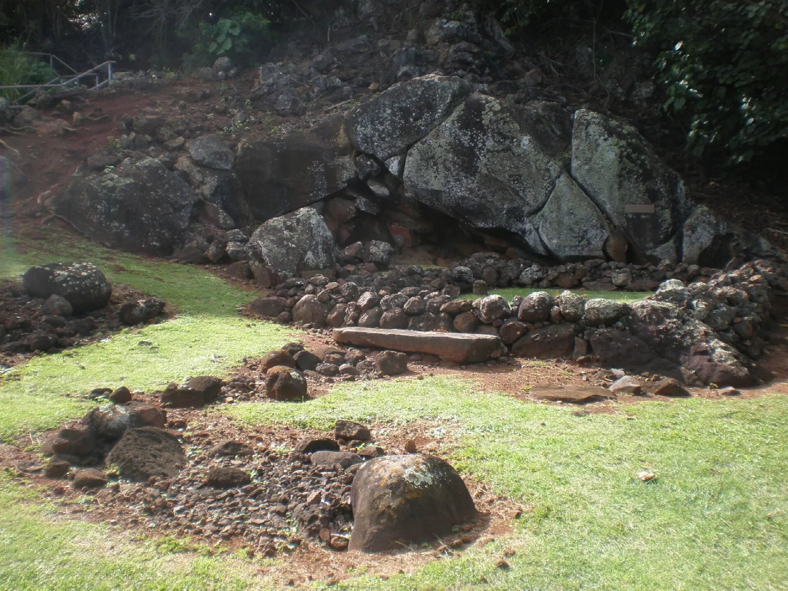 Stacked stones and a flat stone on grass at a heiau site
