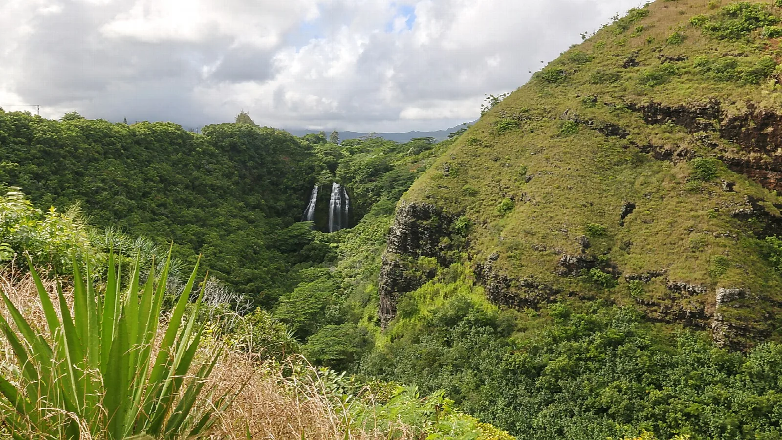 A waterfall seen far across a green valley