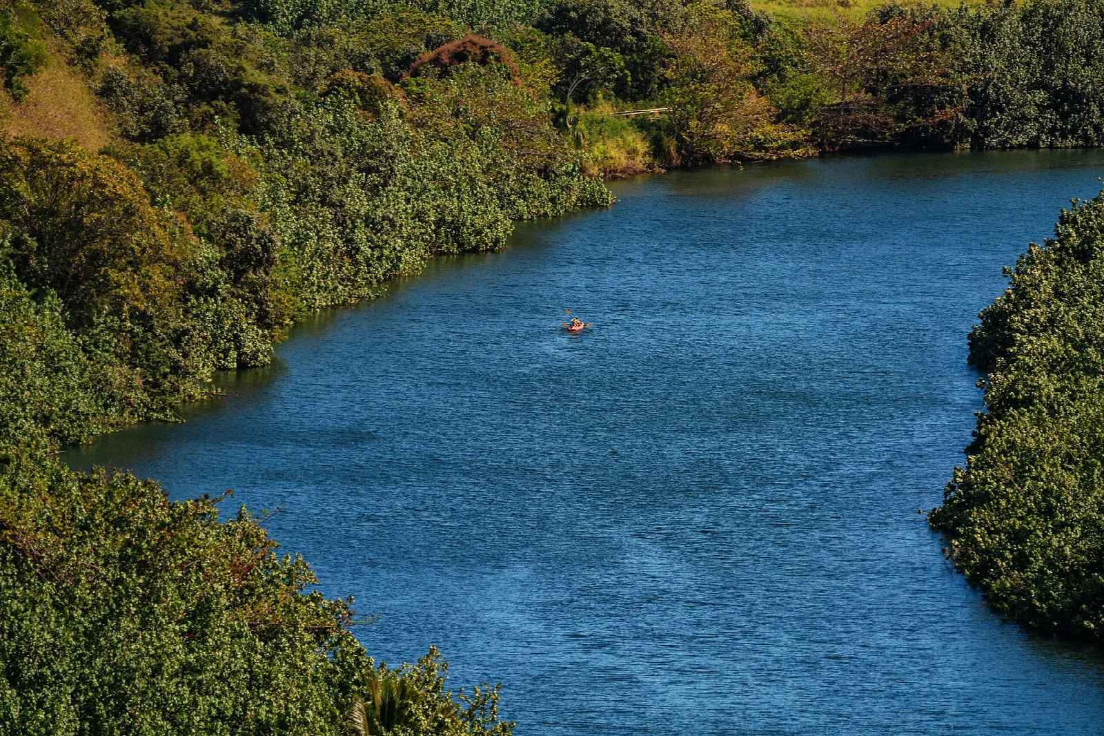 A deep blue river winding between forested hills