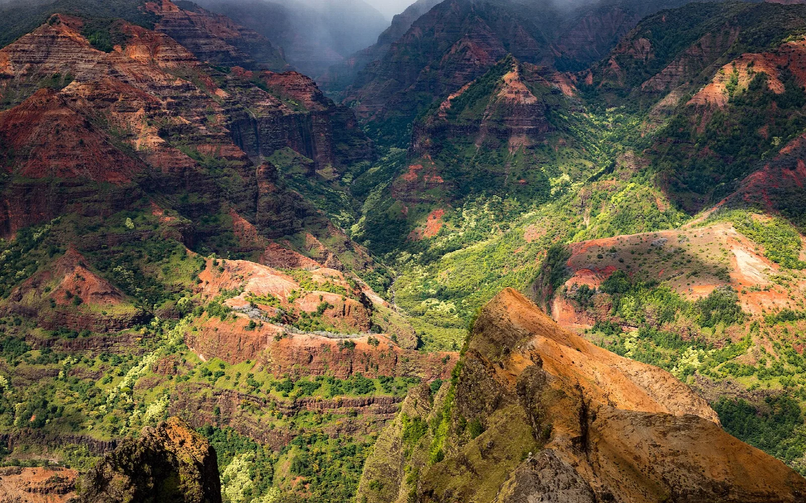 Red rock ridges and green slopes in a deep canyon