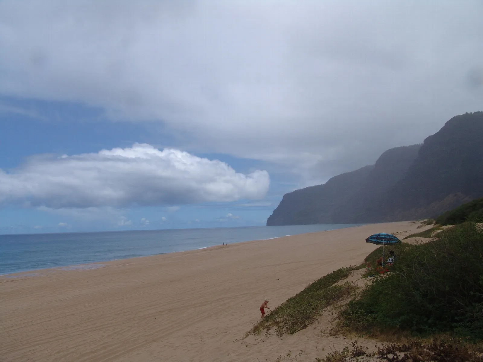 A sandy beach with cliffs fading into cloud