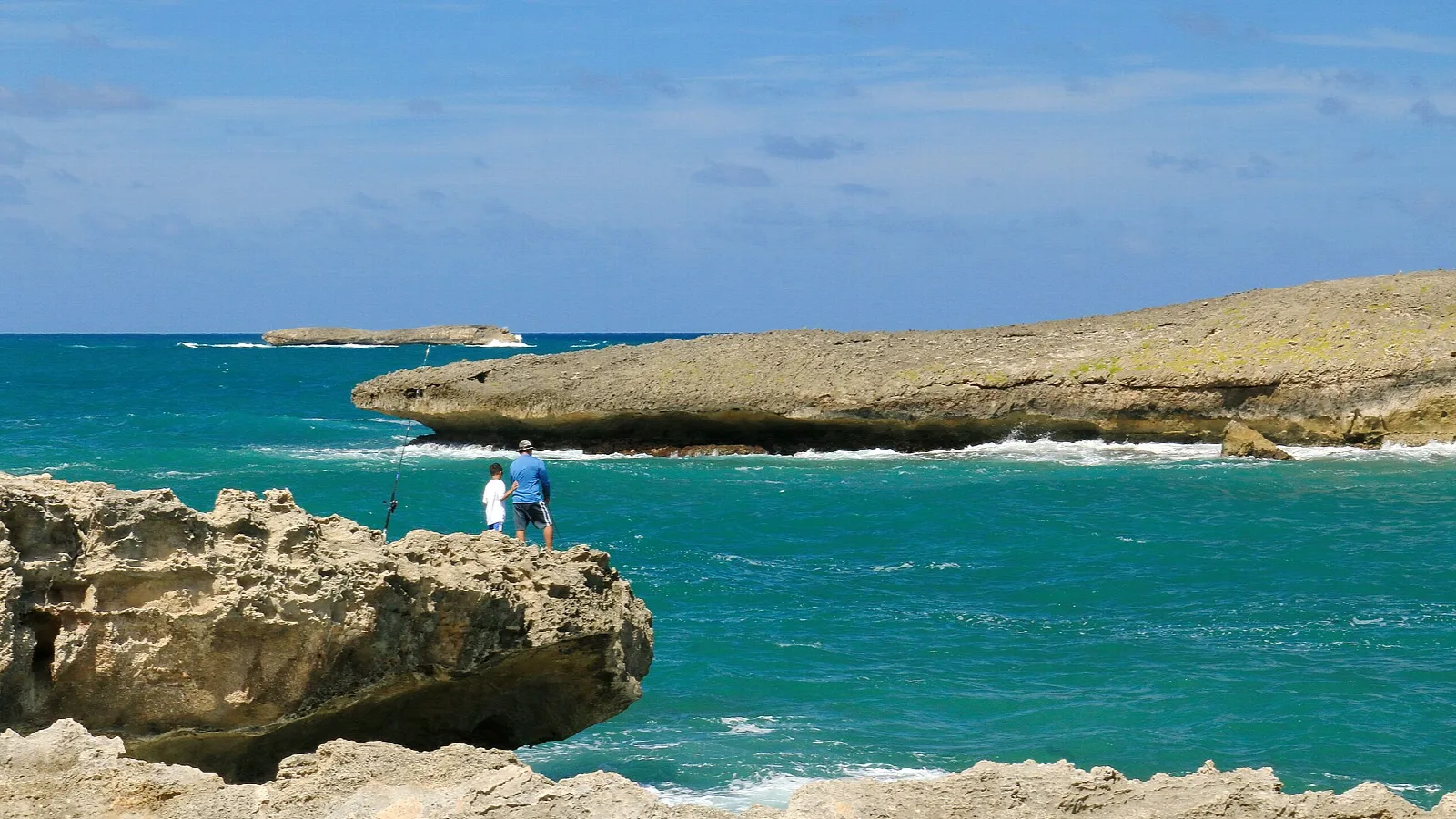 A rock ledge overlooking turquoise water and an offshore island