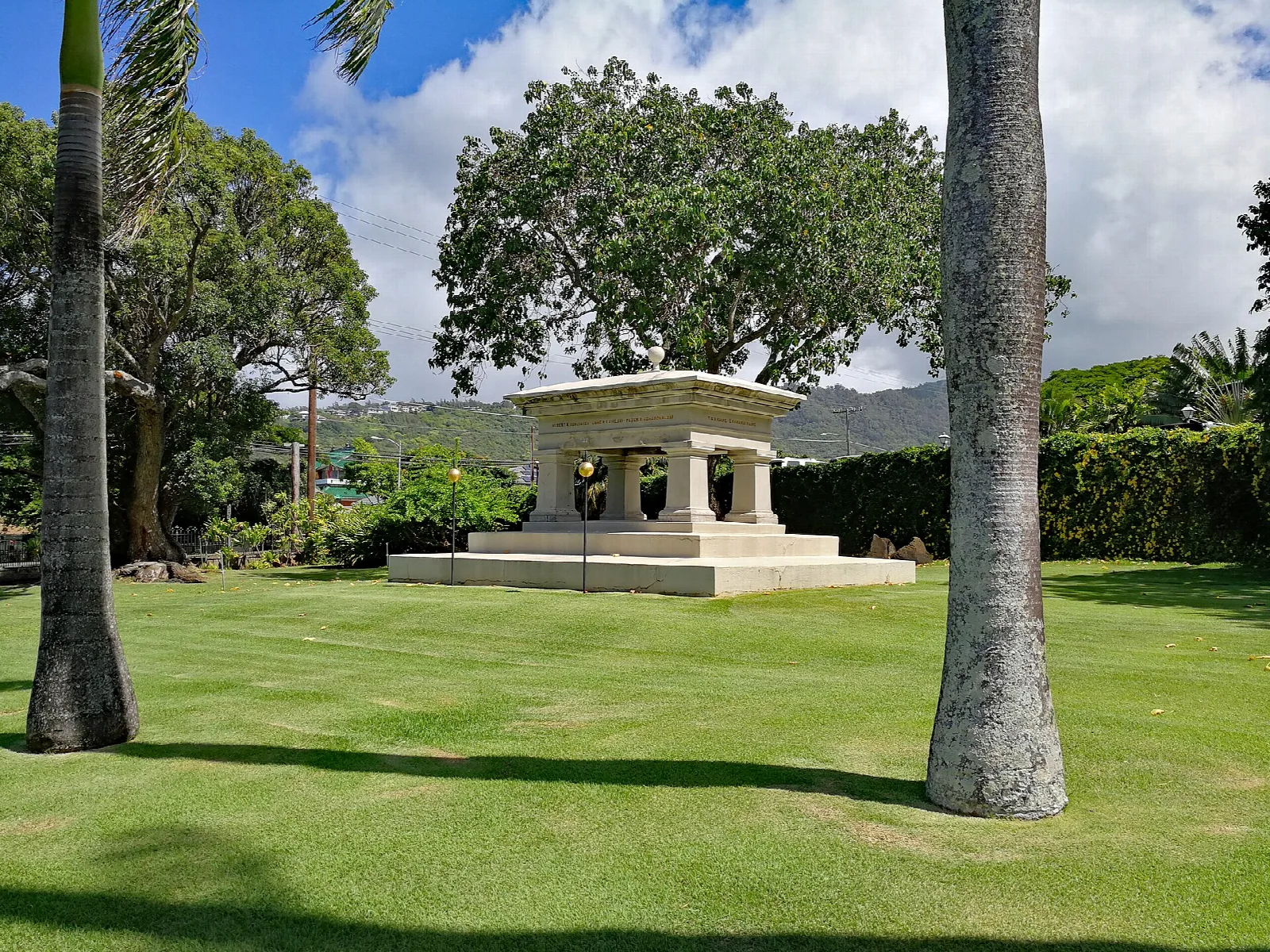 A stone tomb on a lawn between tree trunks