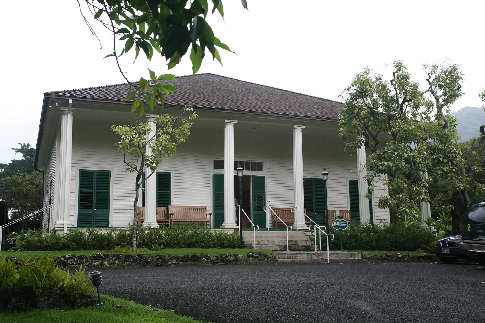 A white house with columns and a gravel drive among trees