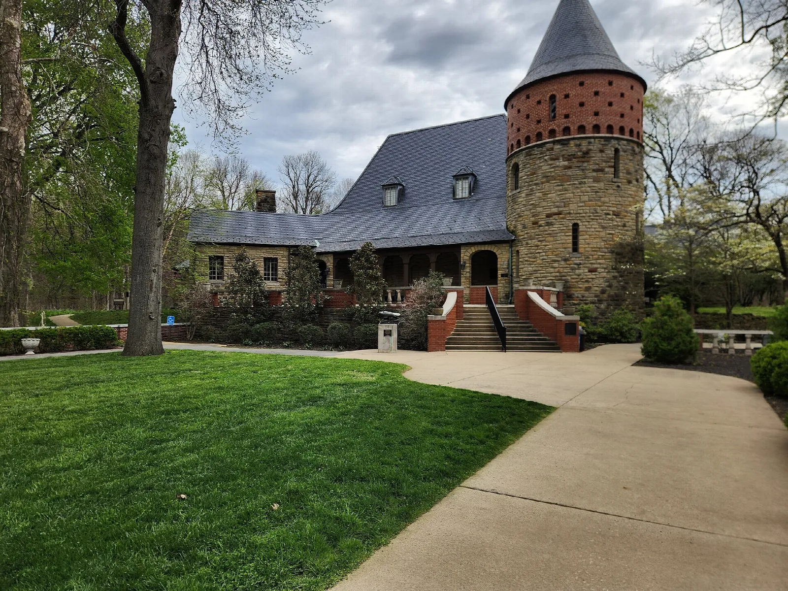 Stone museum building with a round tower, a lawn and a walkway