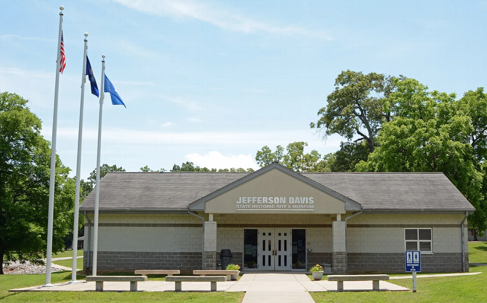 Low building with flagpoles and benches out front