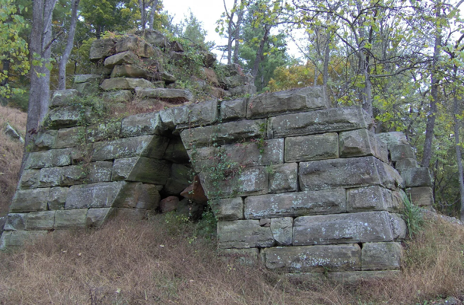 Weathered stone furnace ruin among trees on a hillside