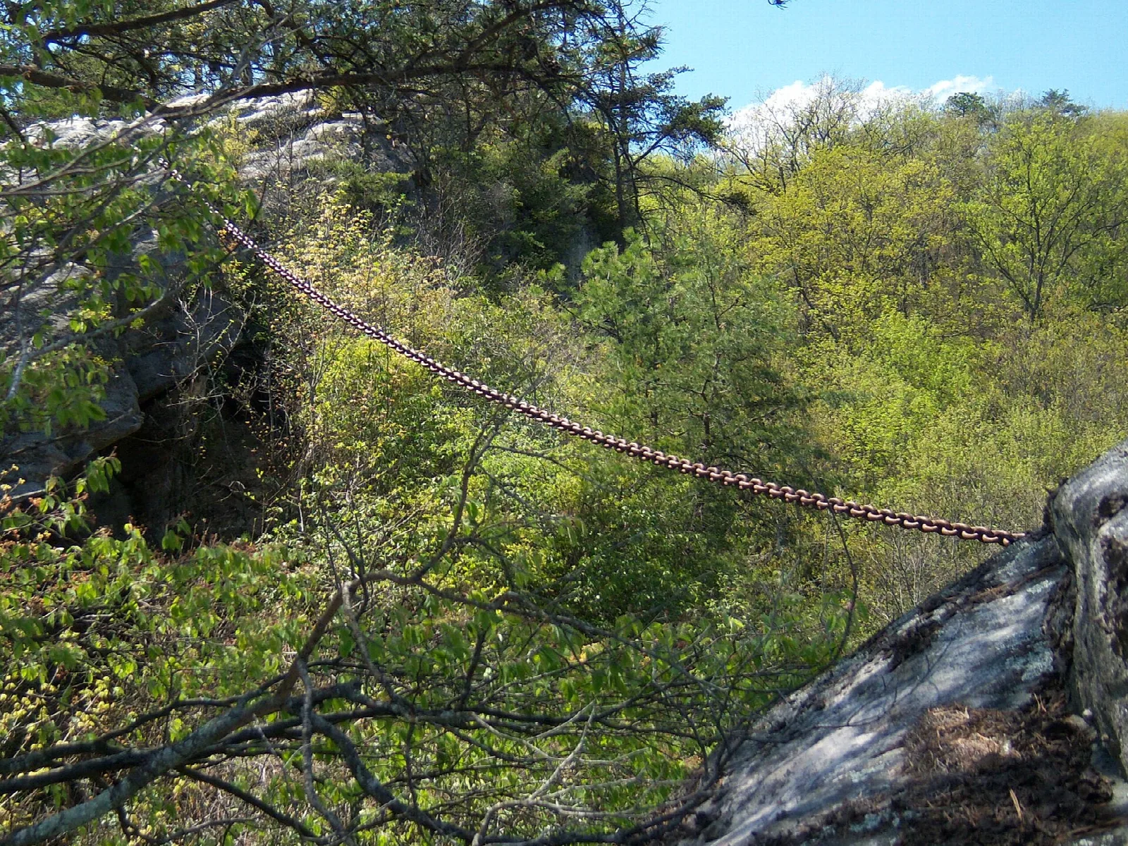 Heavy chain draped across rock ledges among green spring trees